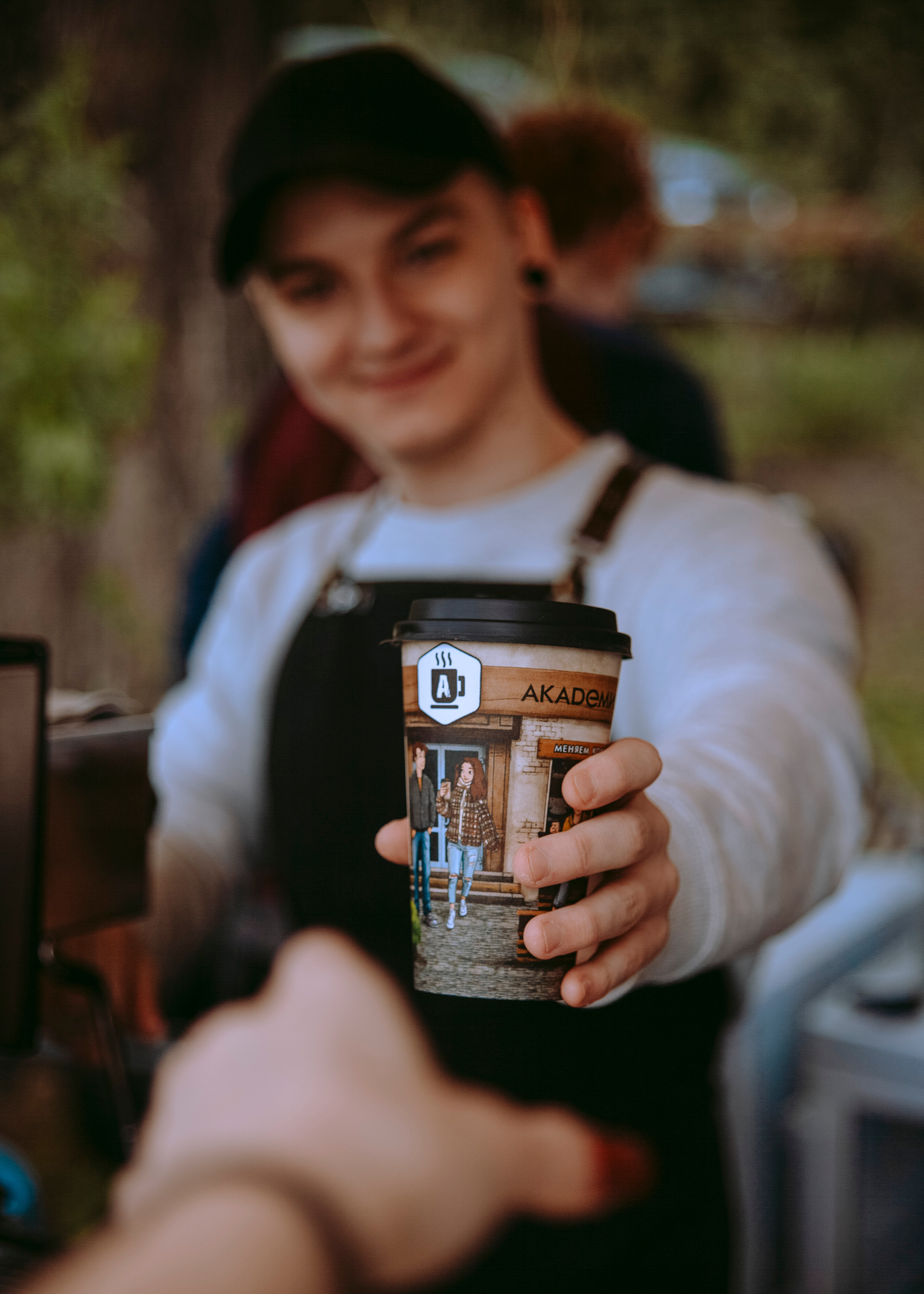 Бариста протягивает кофе.