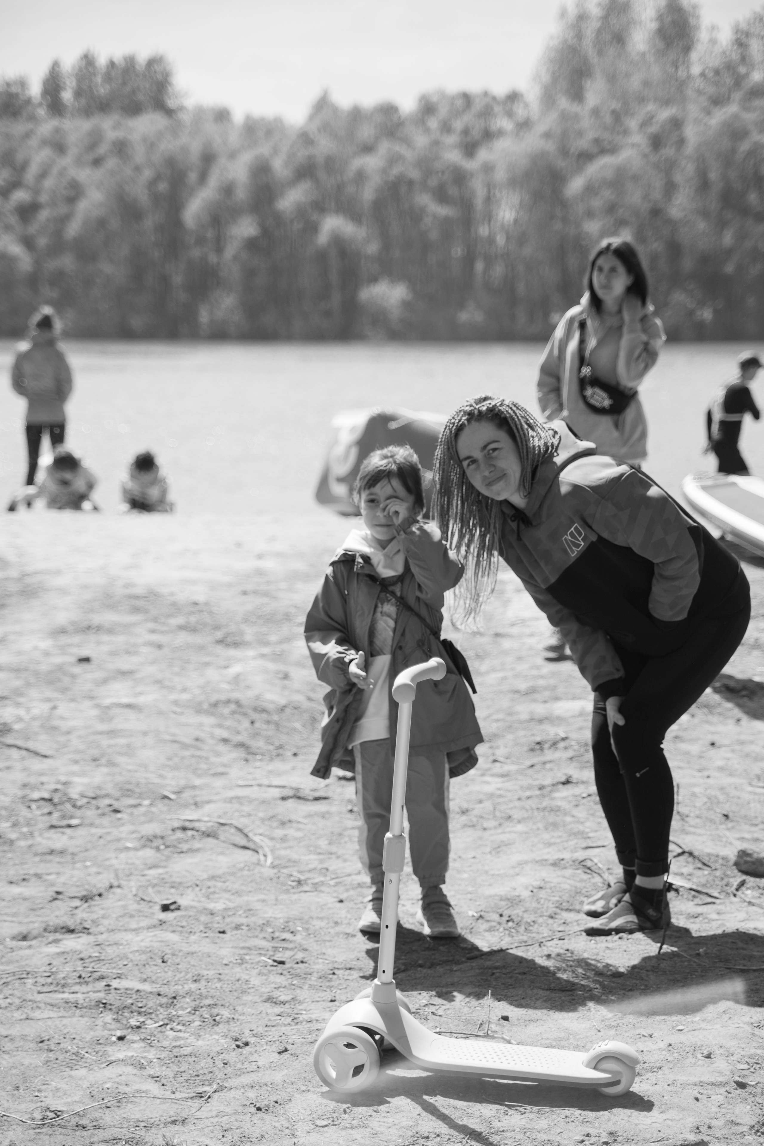 Девушка с косичками рядом с дочкой на самокате.