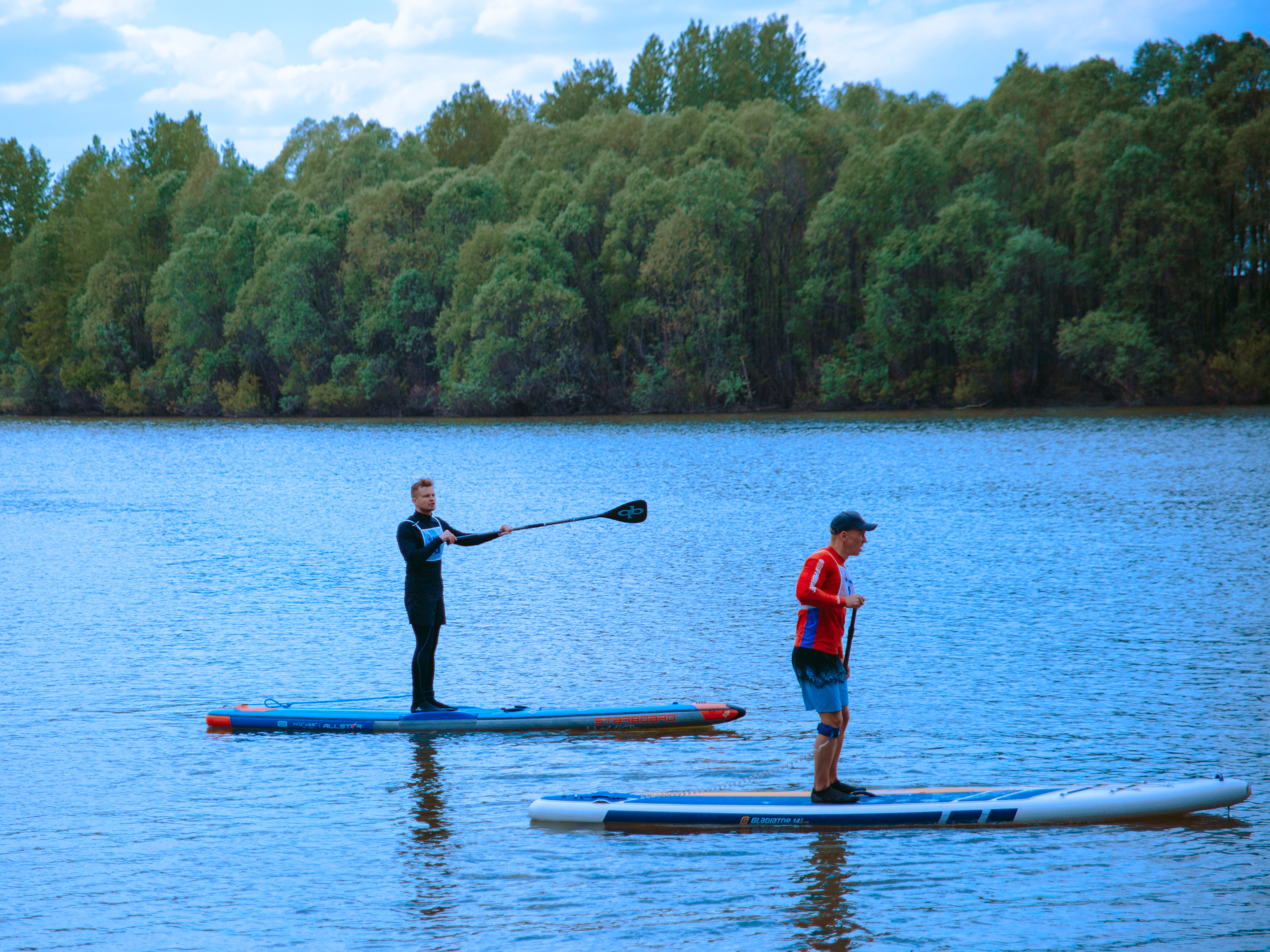Два мужчины катаются на сапах по воде.