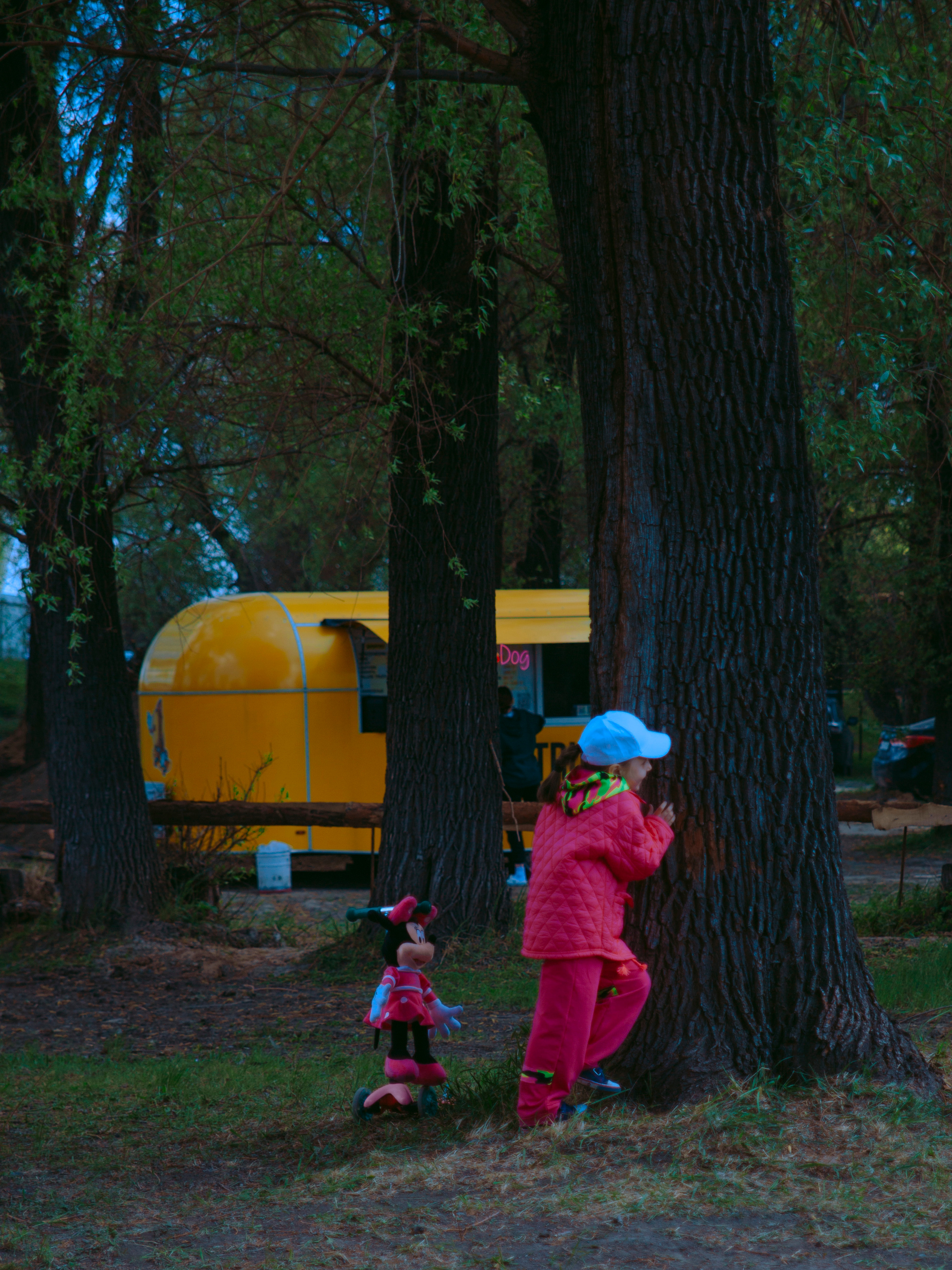 Девочка прячется за деревом.