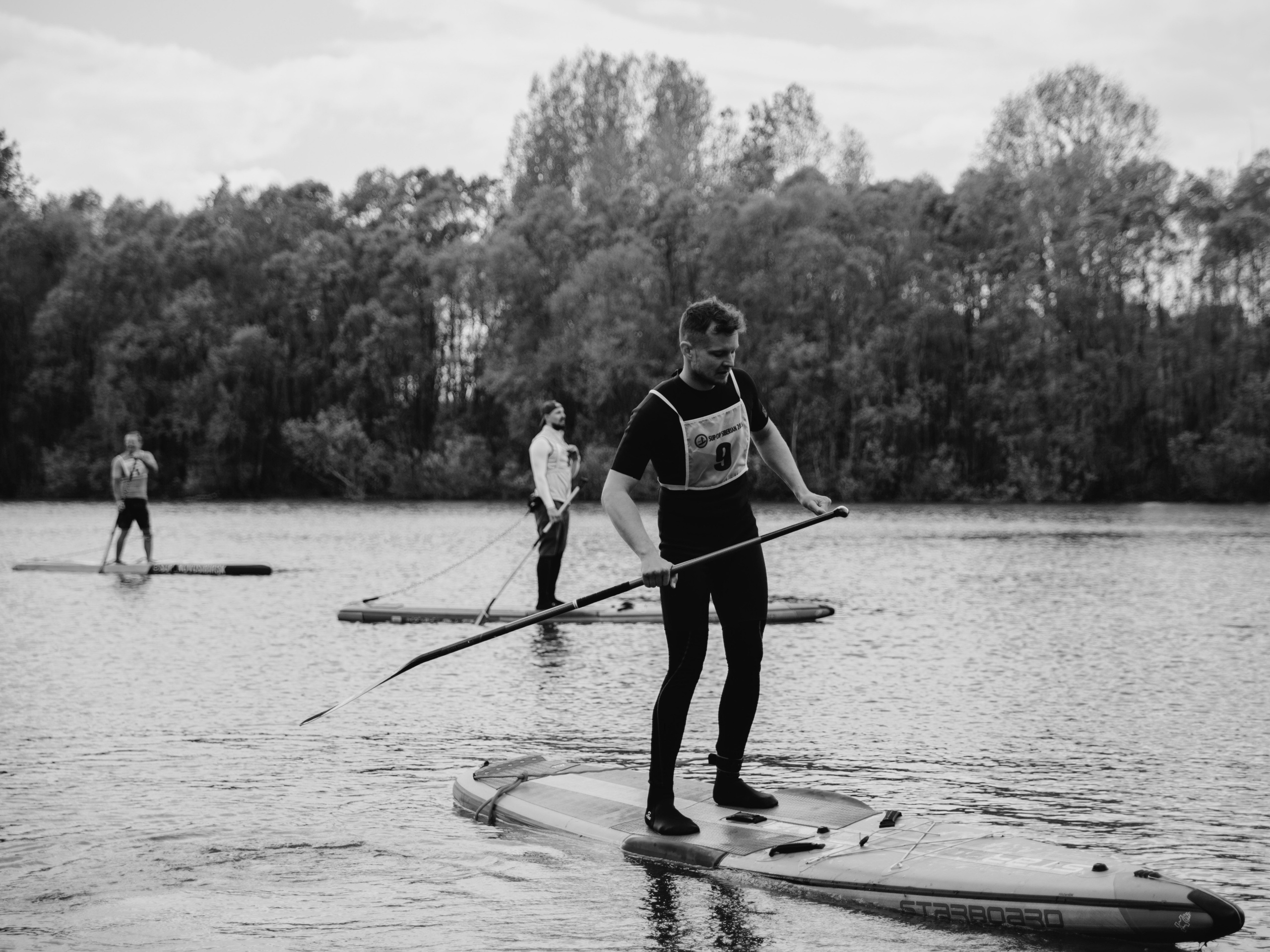 Черно-белое фото мужчины на соревнованиях по водному виду спорта.