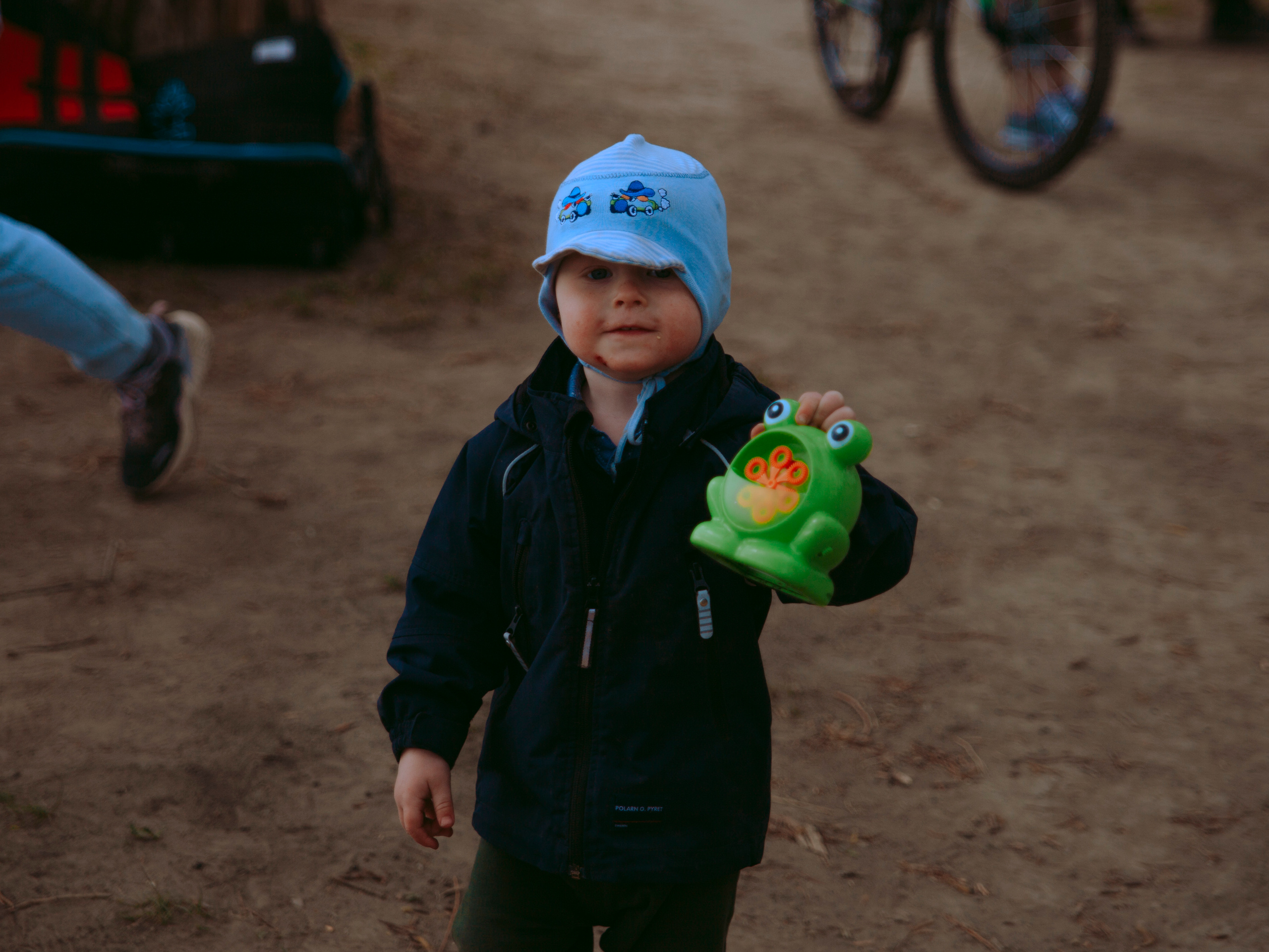Ребенок с игрушкой лягушкой в парке.