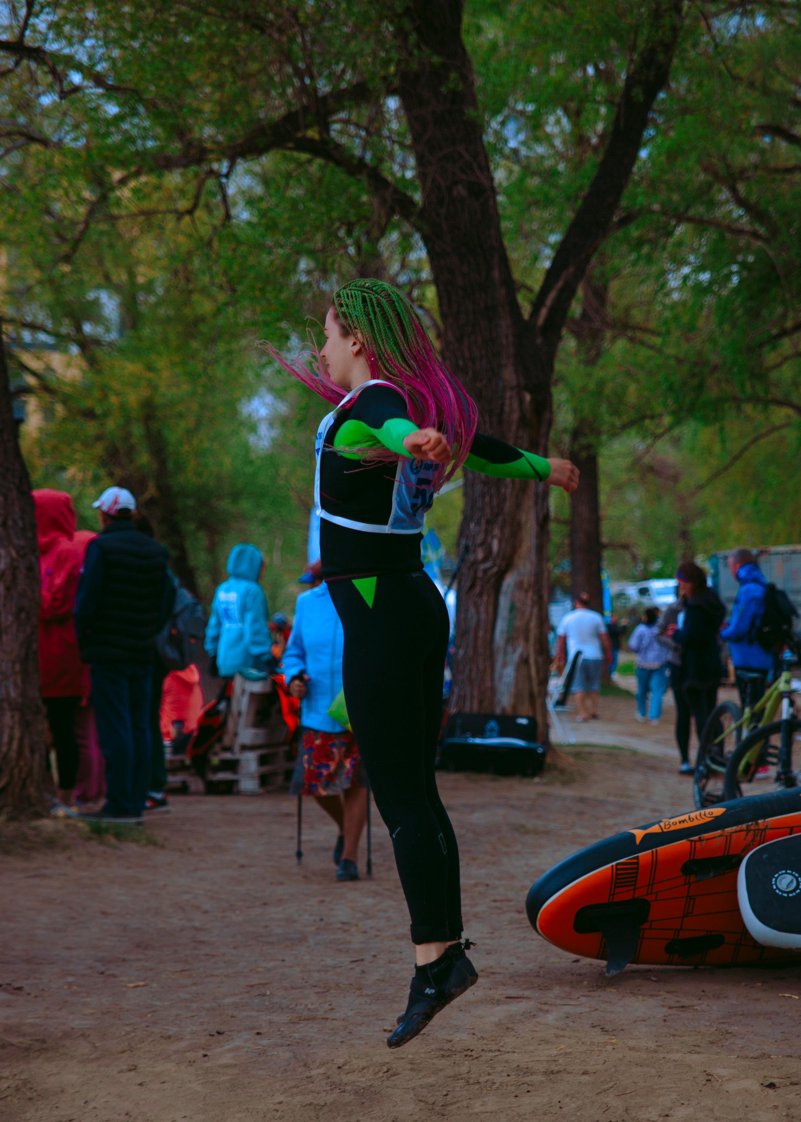 Девушка спортсменка с цветными косичками в гидрокостюме подпрыгнула в воздух.