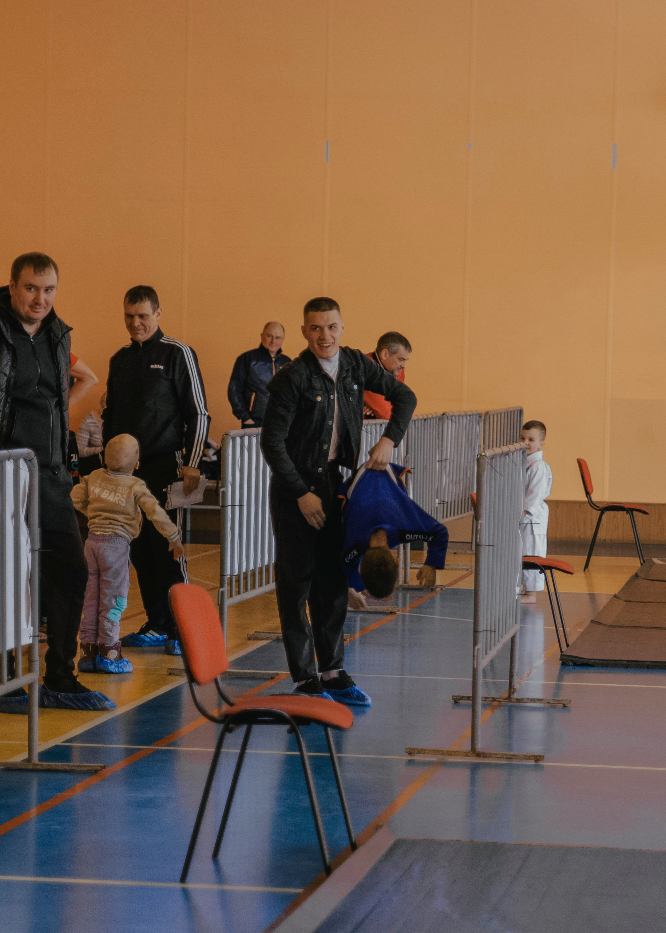 Папа держит на руках ребенка спортсмена и играет с ним.