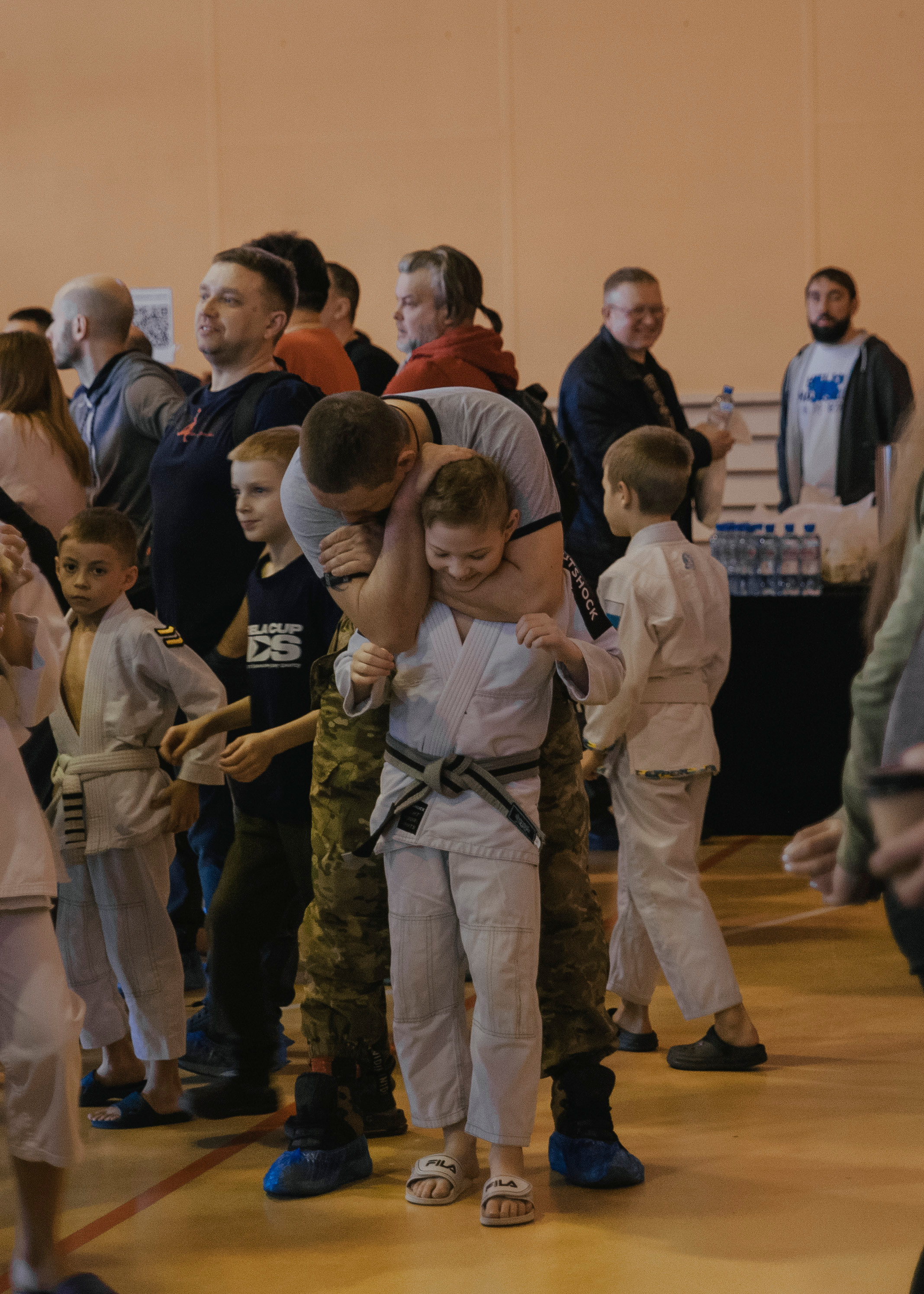 Тренер показывает приём спортсмену  на детском турнире по джиу-джитсу.