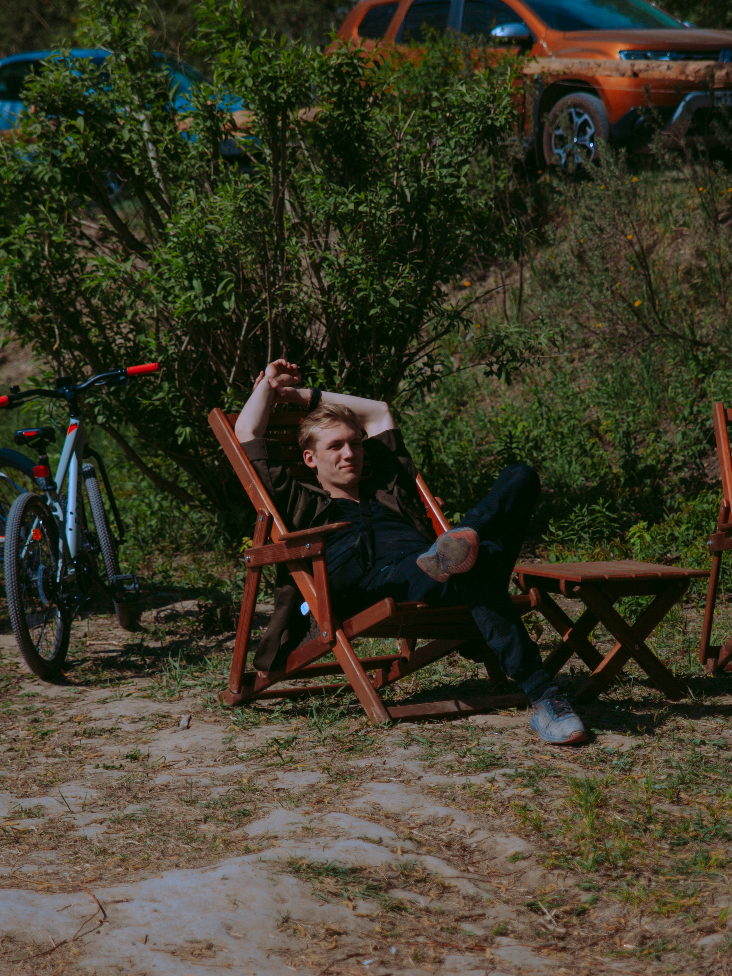 Парень лежит в кресле в парке.