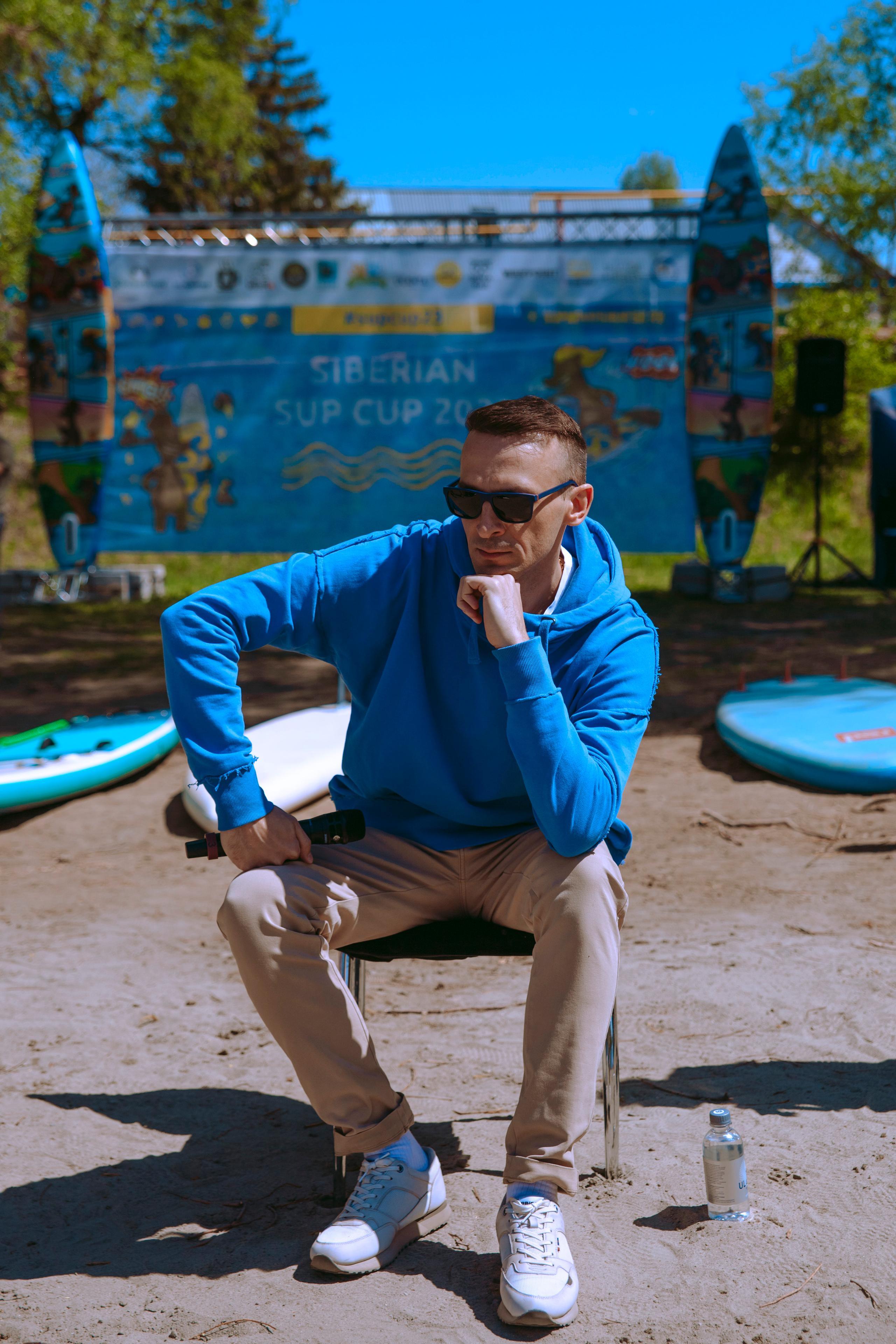 Ведущий мероприятия Денис Метелёв сидит на стуле в солнечный день и позирует.