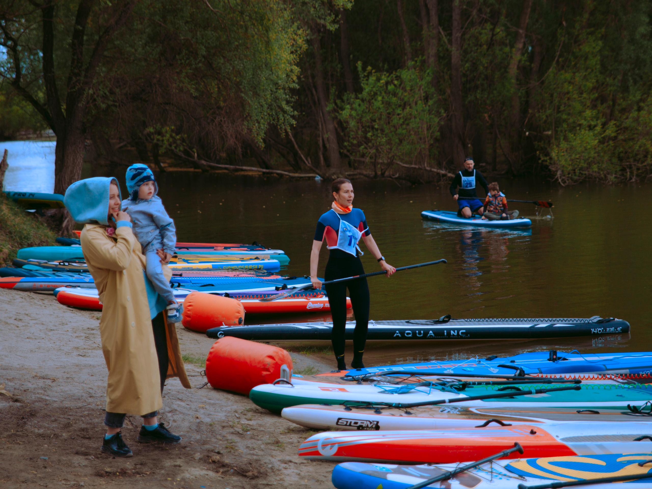 Спортсмены на берегу на фоне леса.