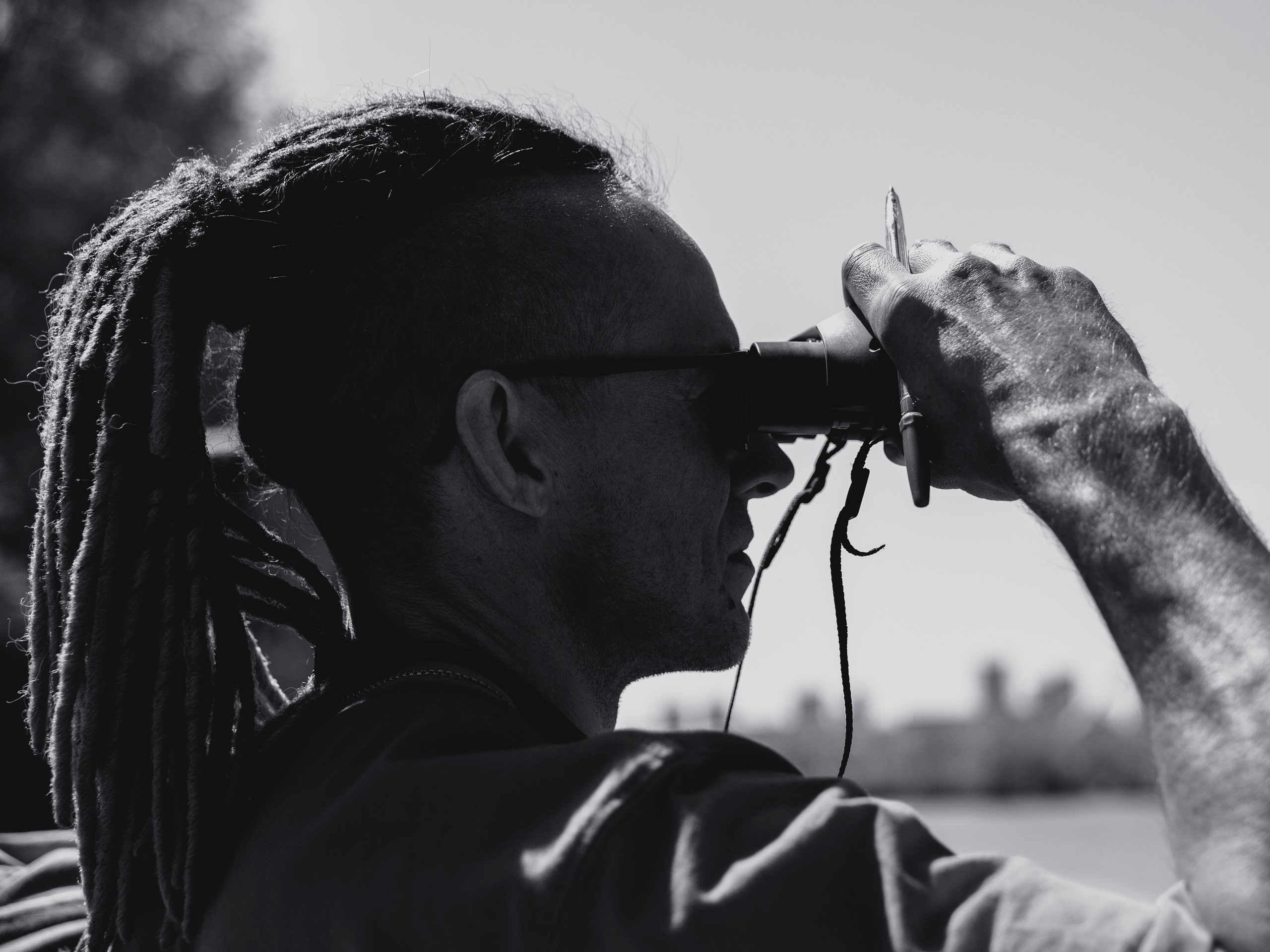 Тренер судья с дредами, собранными в хвост, смотрит в бинокль.