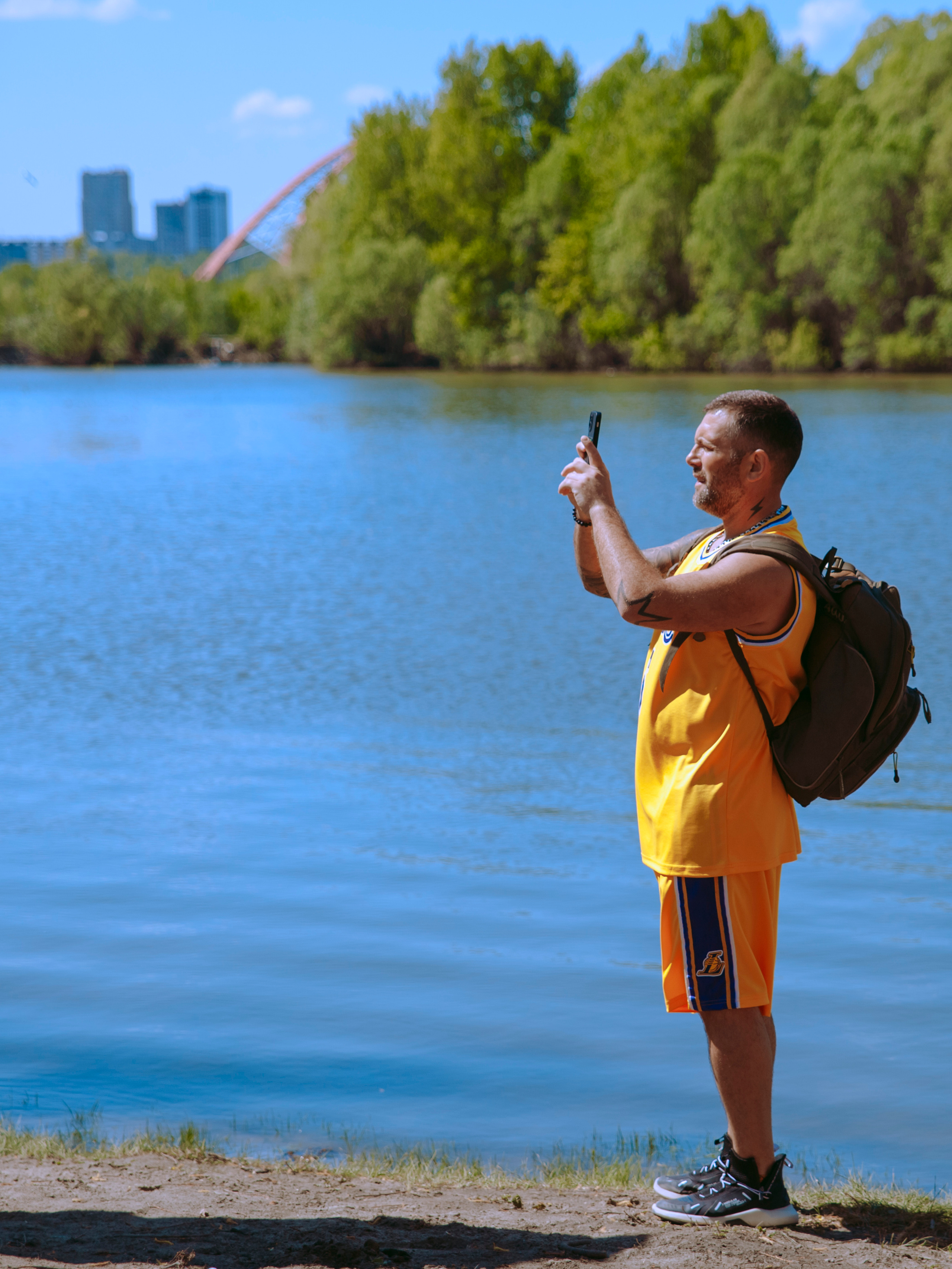 Спортивный мужчина в желтом костюме снимает на телефон.