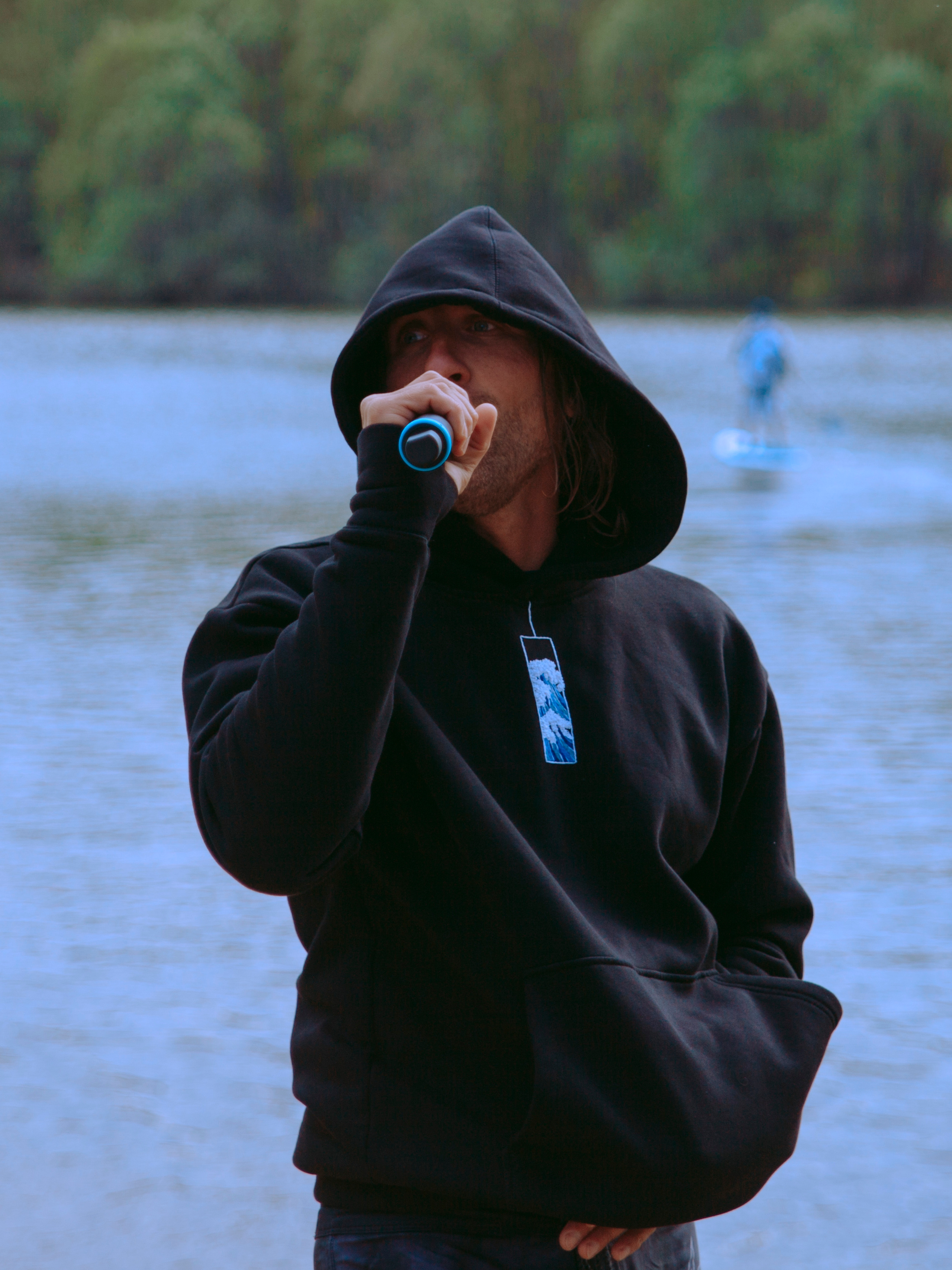 Мужчина поет в микрофон на берегу.