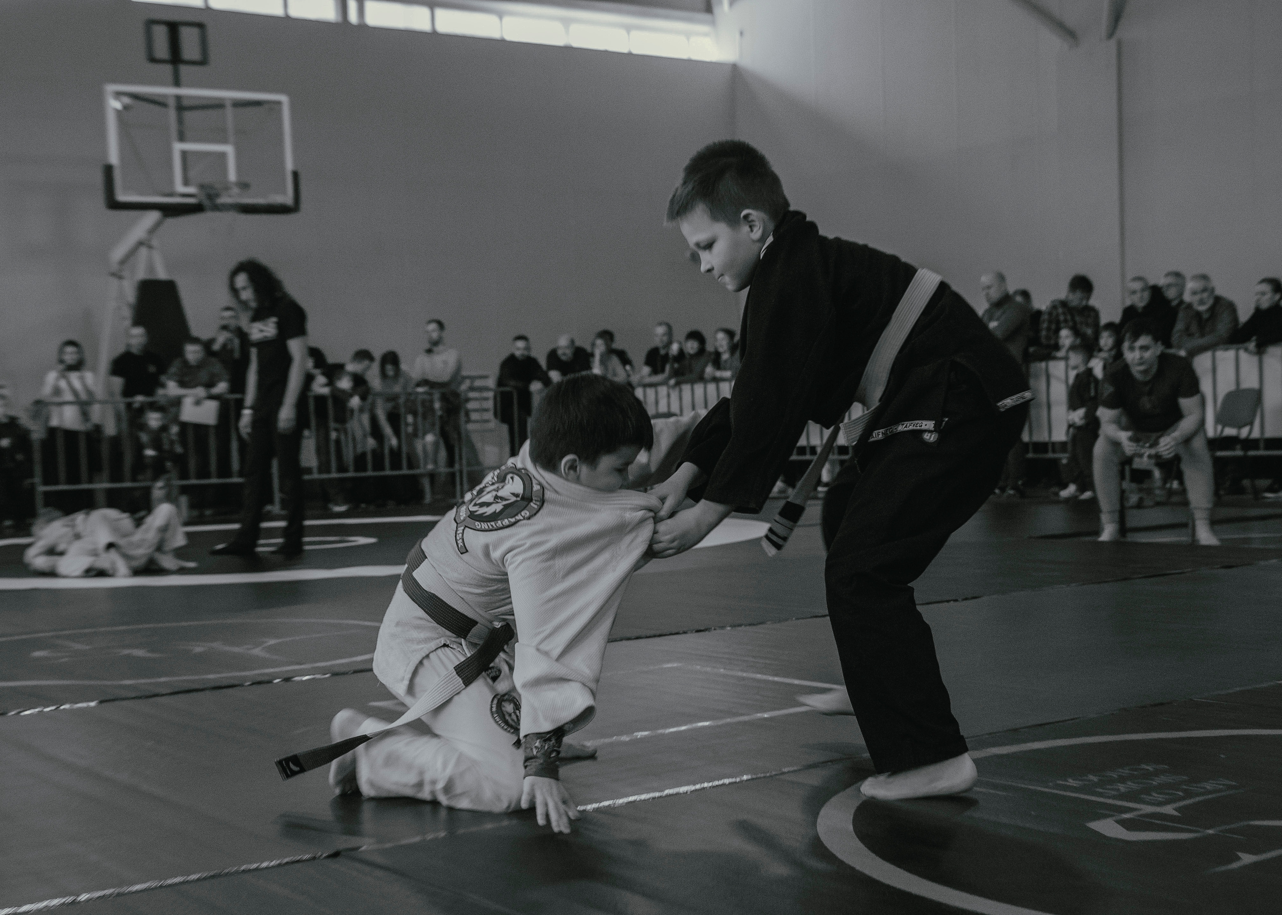 Напряженная борьба в кимоно gi на детском турнире по джиу-джитсу.