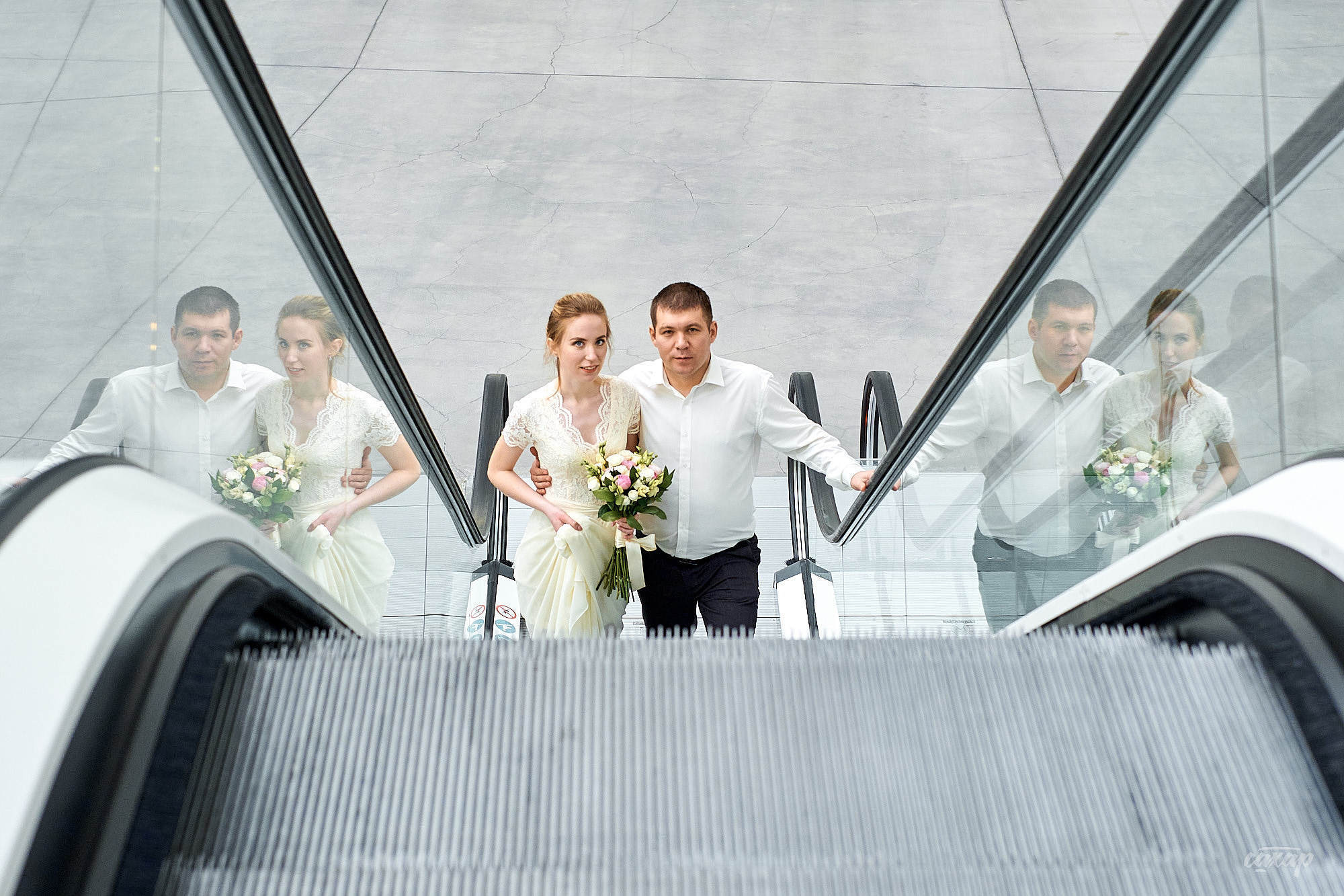 невеста с женихом поднимаются по эскалатору вверх