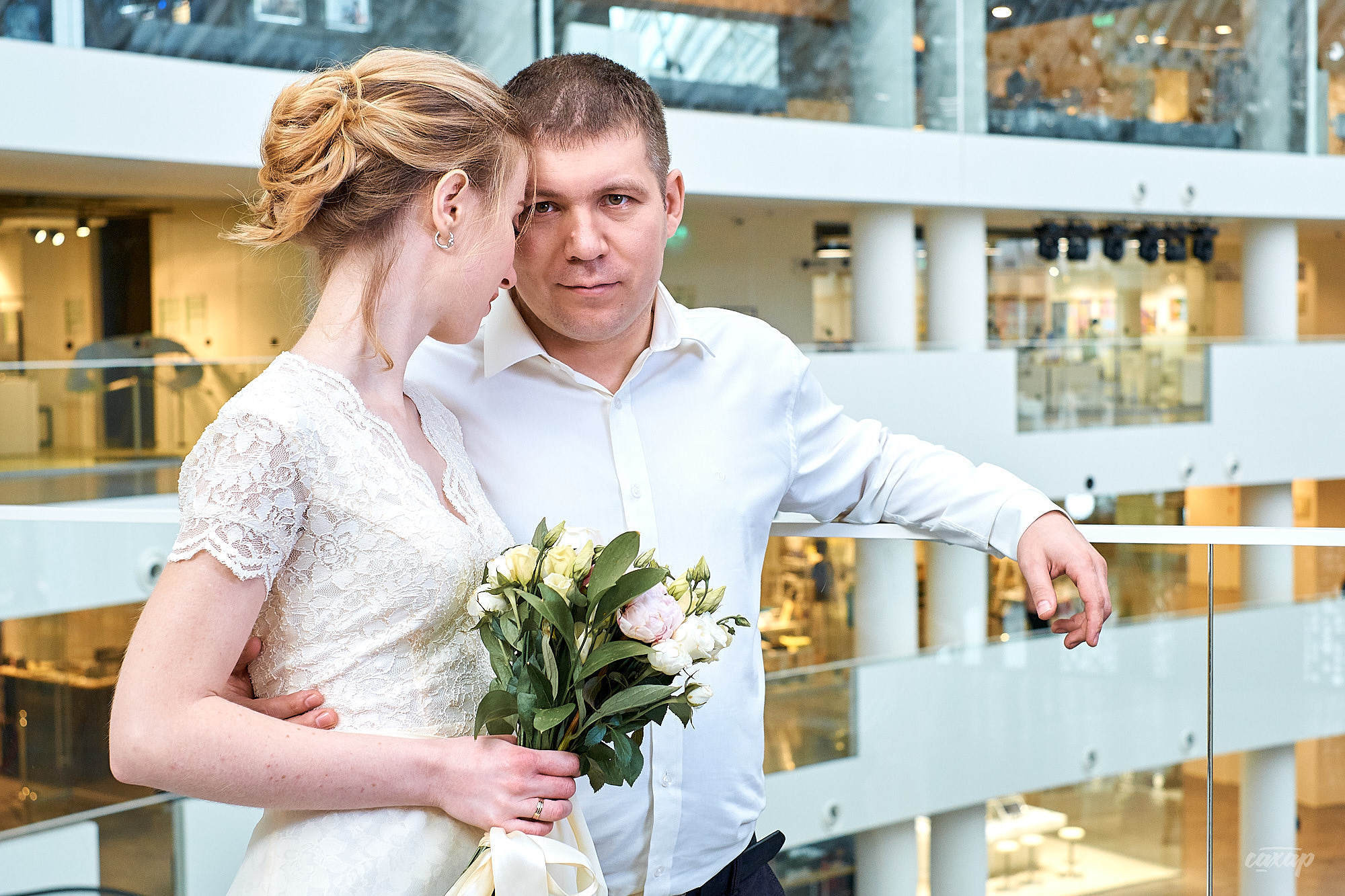 жених обнимая невесту смотрит в обьектив свадебного фотографа