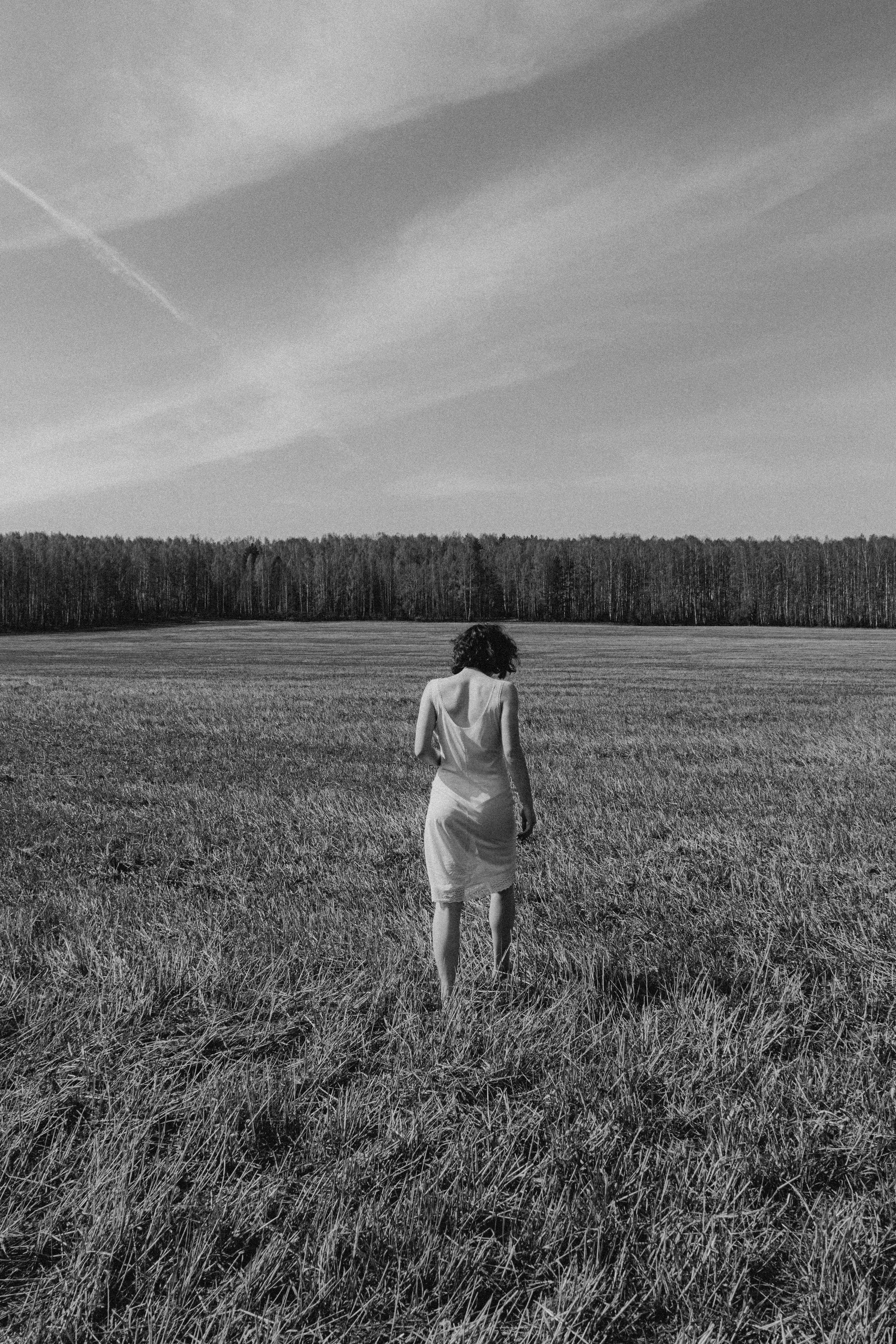 Модель в белом платье идёт по полю 