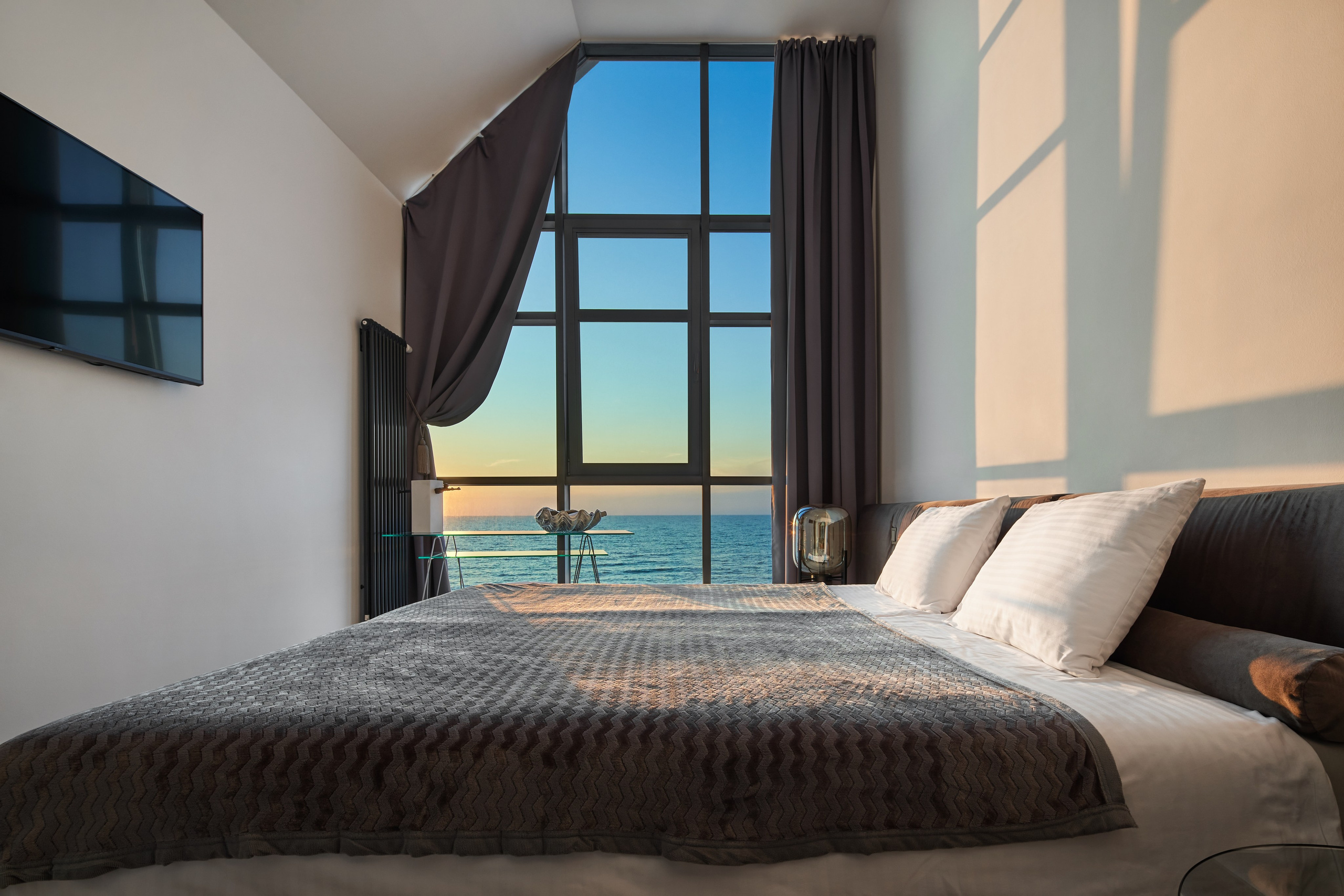 Просторная спальня с видом на море на закате.