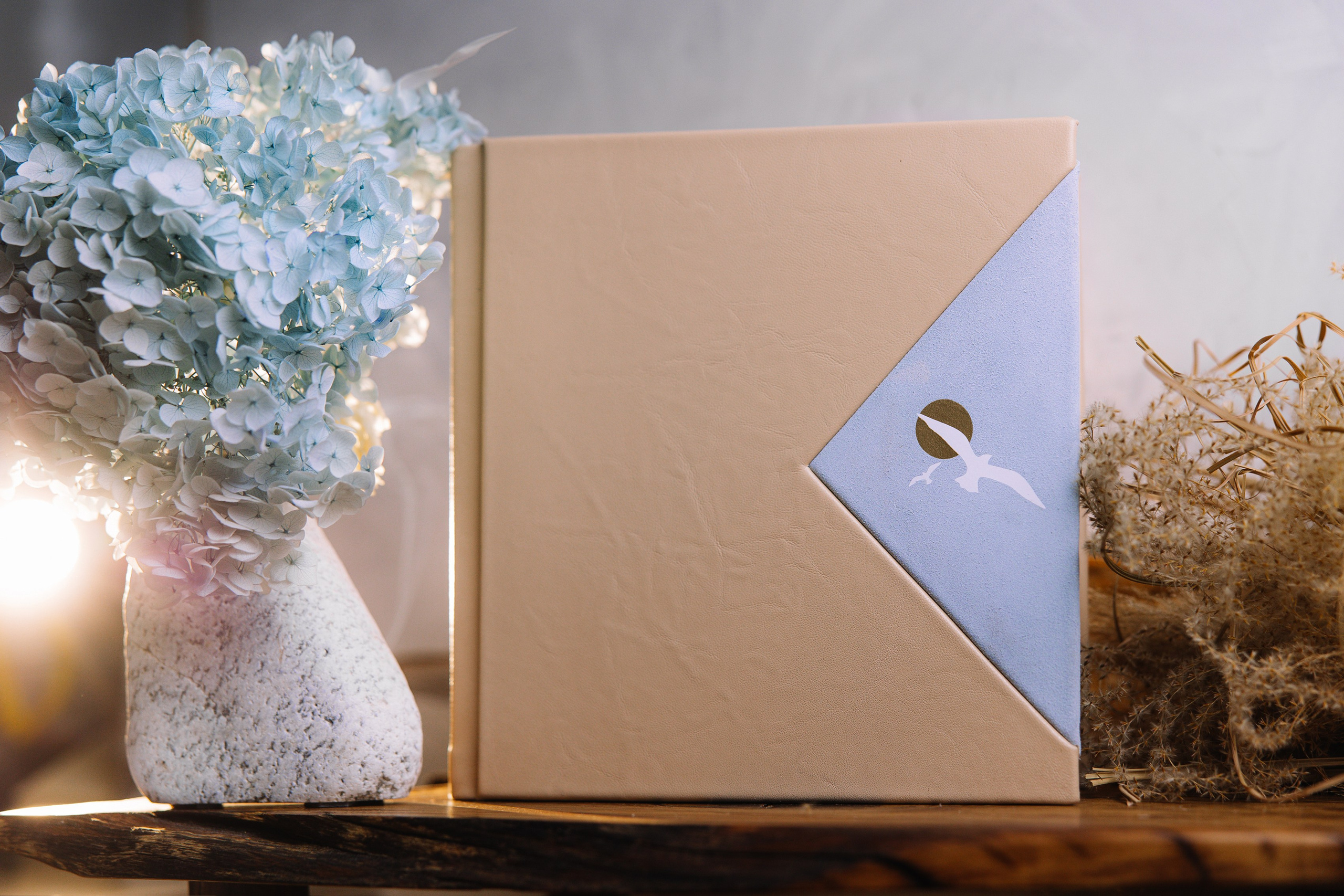 Фотокнига в комбинированной обложке из бежевой кожи и голубой замши с изображением летящей чайки