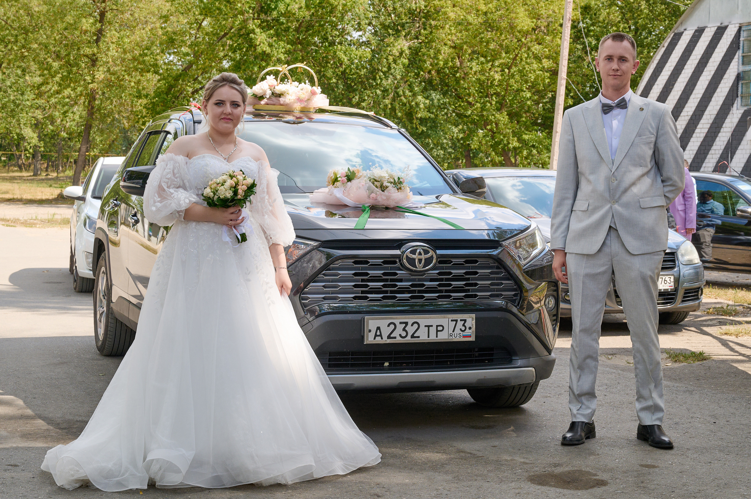 жених с невестой возле свадебного автомобиля