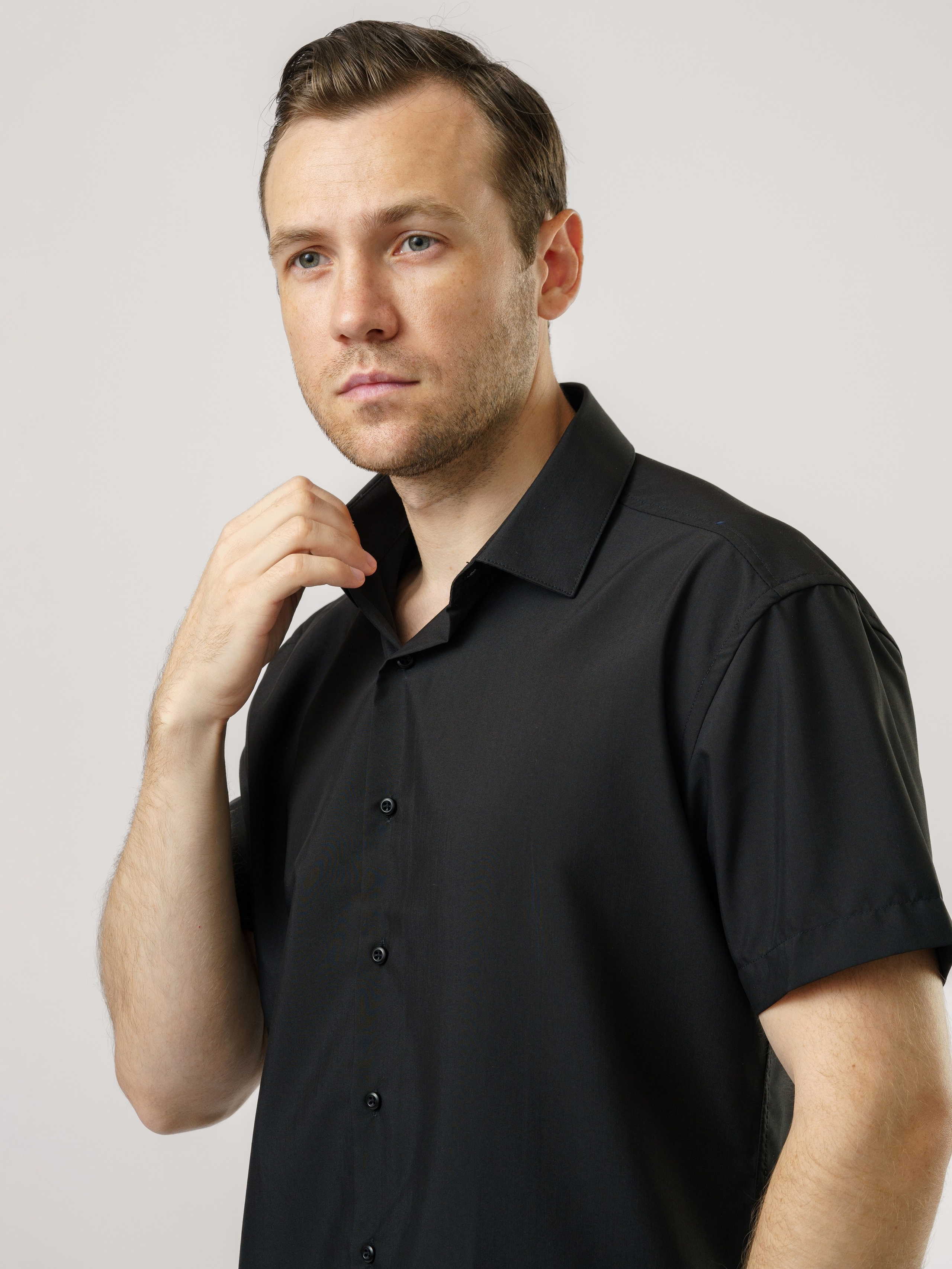 Мужчина с короткой щетиной в черной рубашке коротким рукавом