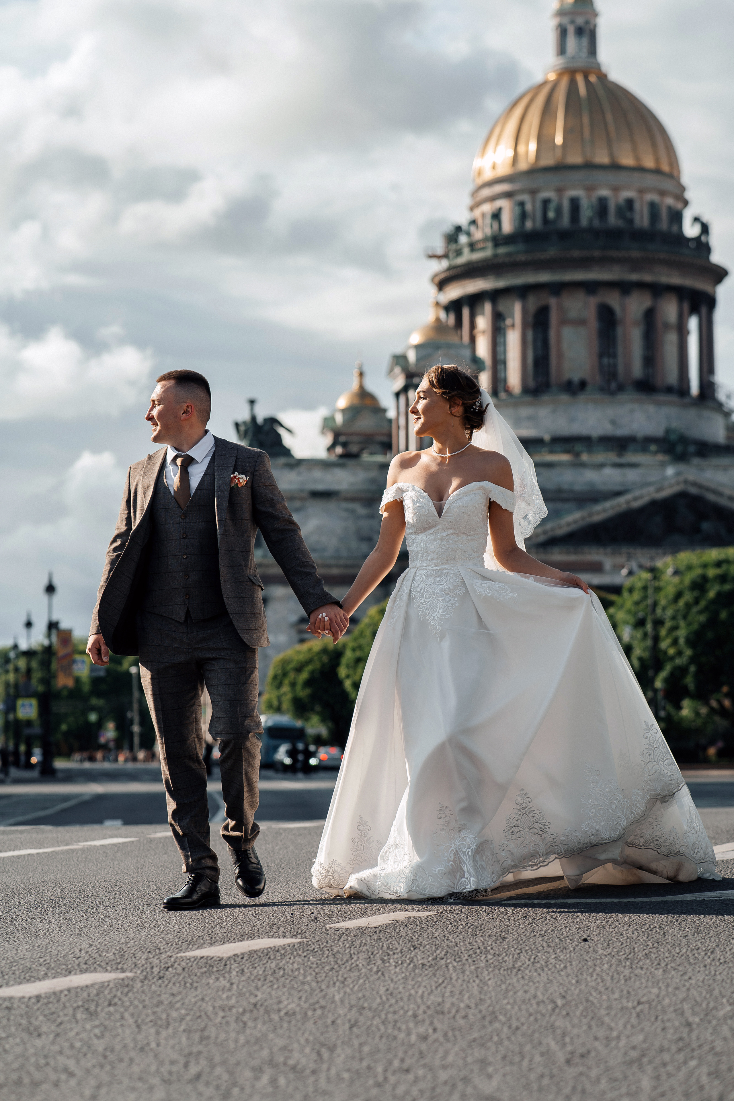 Жених и невеста гуляют по дороге на фоне Исаакиевского собора