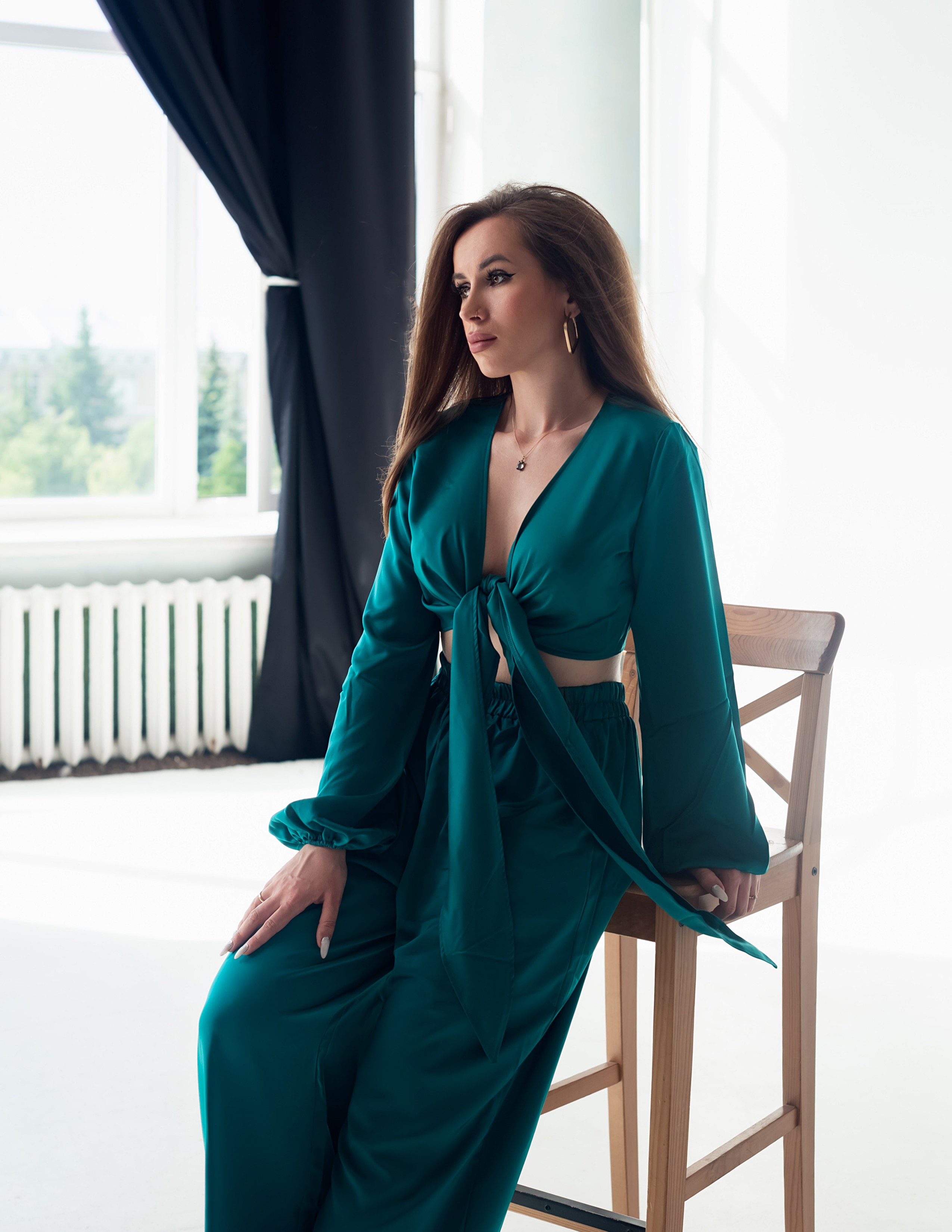 Красивая девушка в изумрудном костюме пижамного стиля, фотоссесия на циклораме в студии.