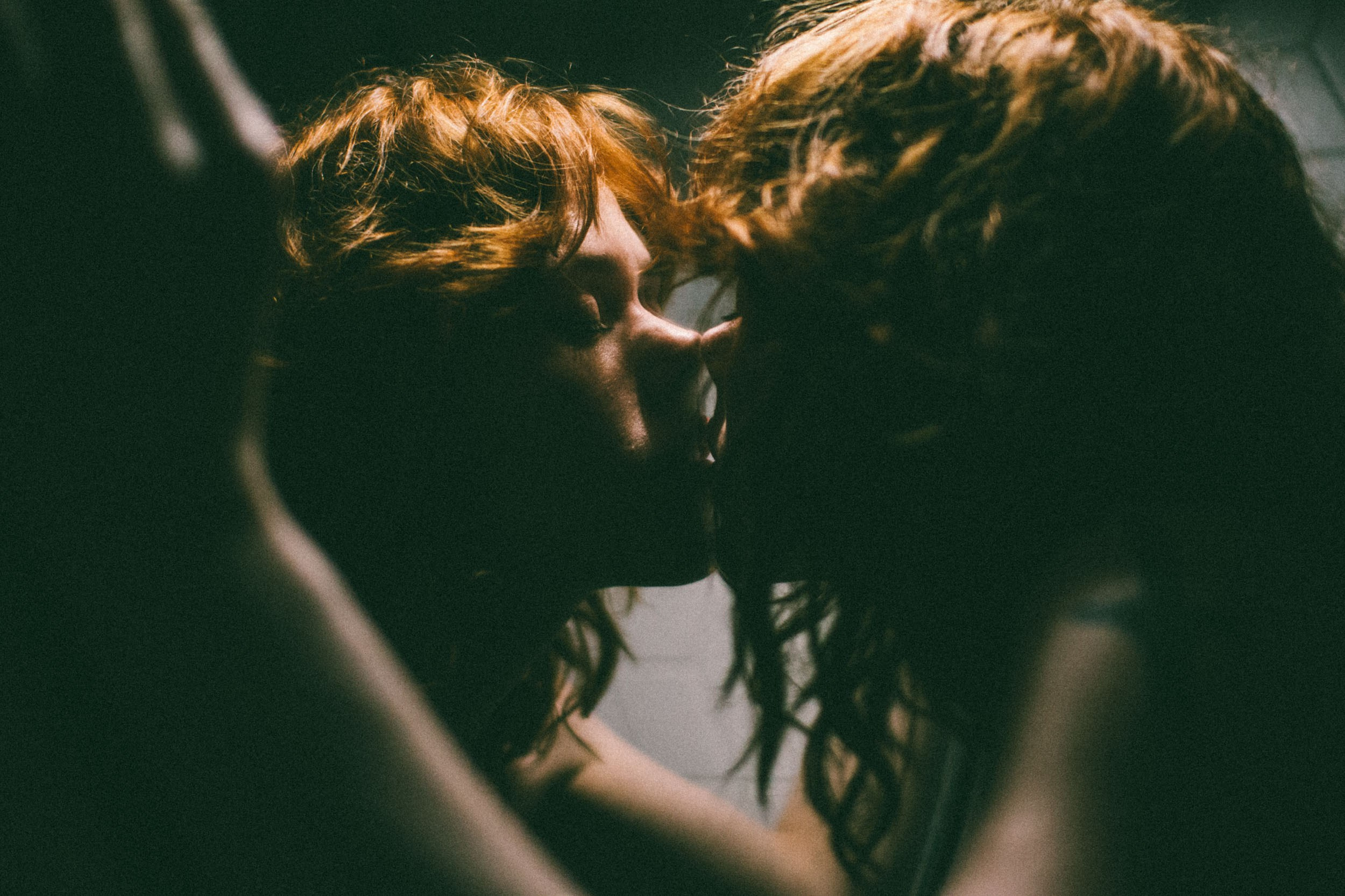 Рыжеволосая девушка целует свое отражение в зеркале