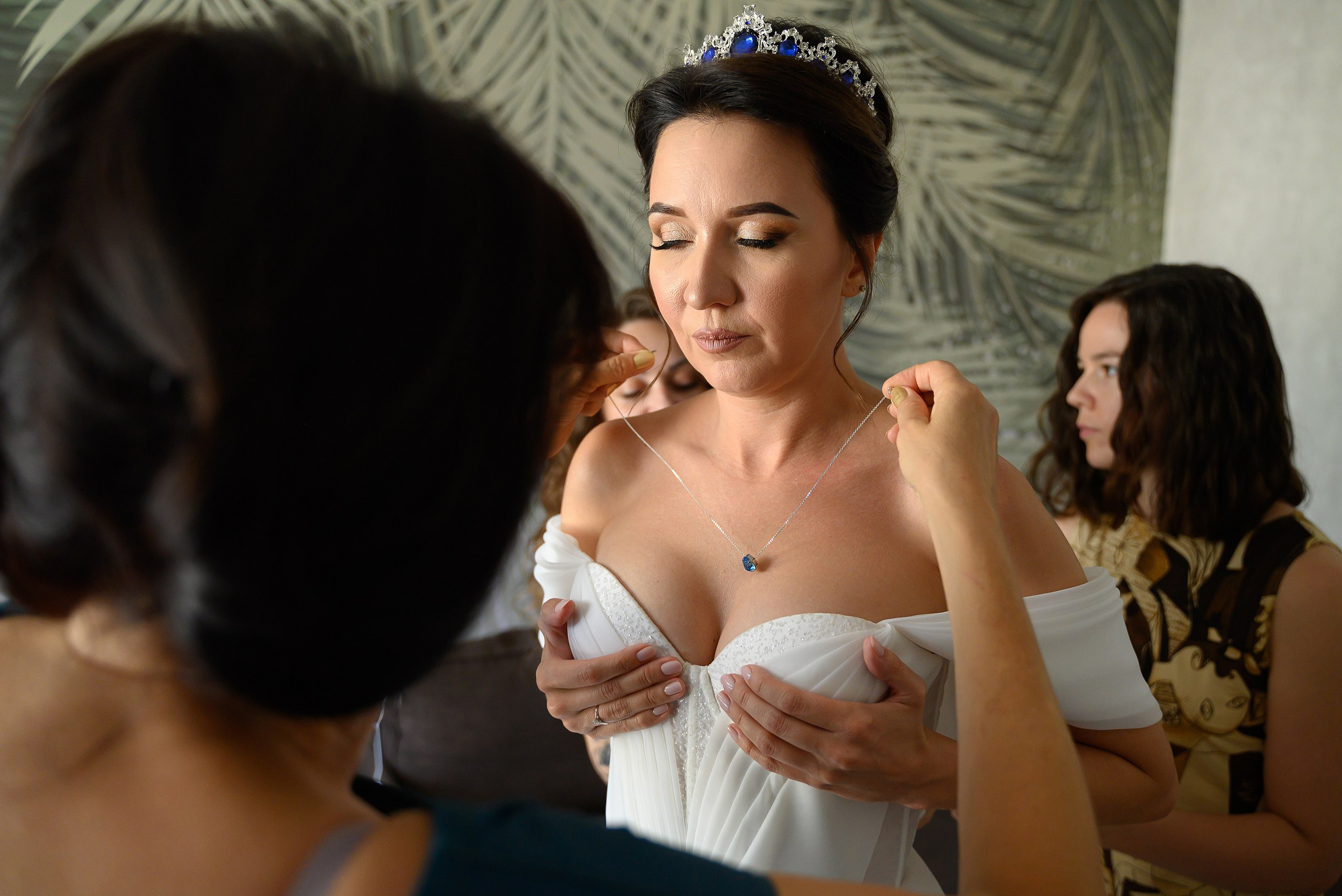 Подружки невесты надевают колье невесте.