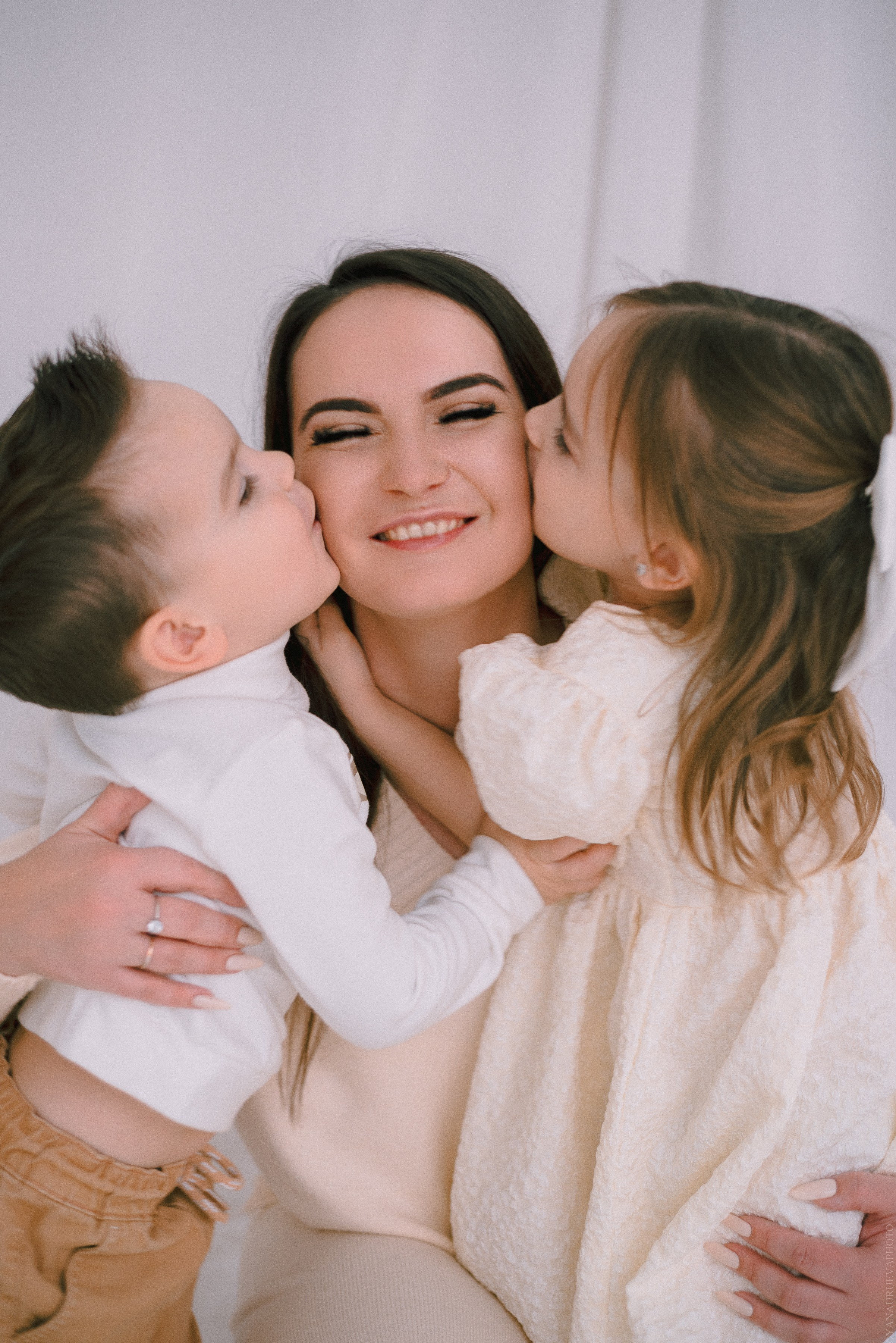 сын и дочка целуют маму в щеку