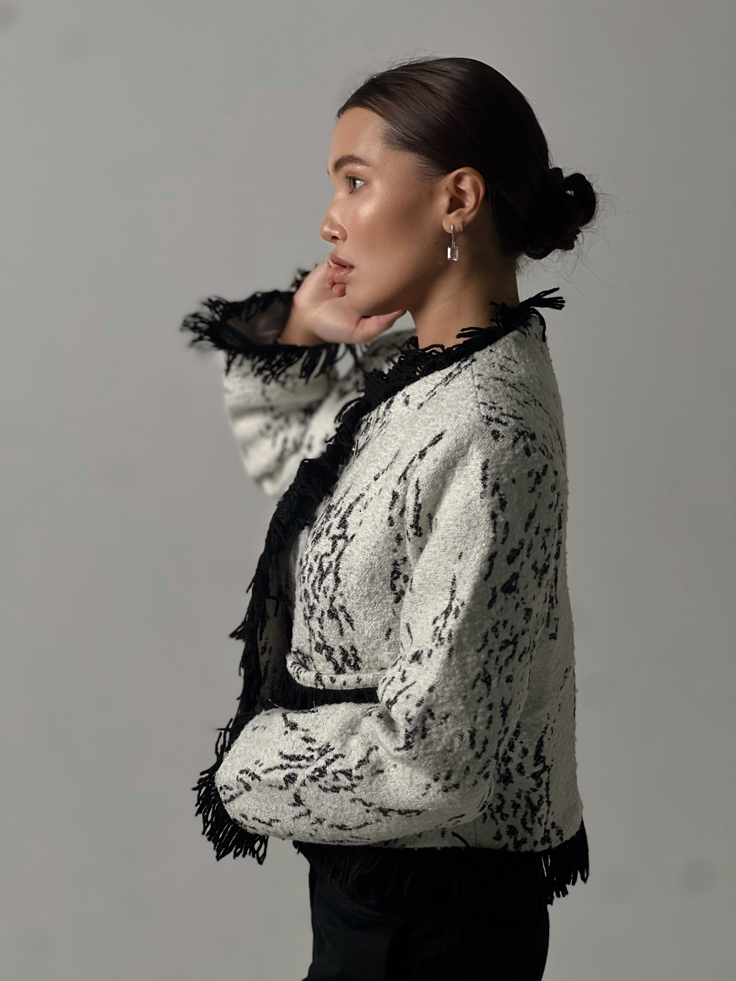 Девушка азиатской внешности позирует в светлом жакете на сером фоне