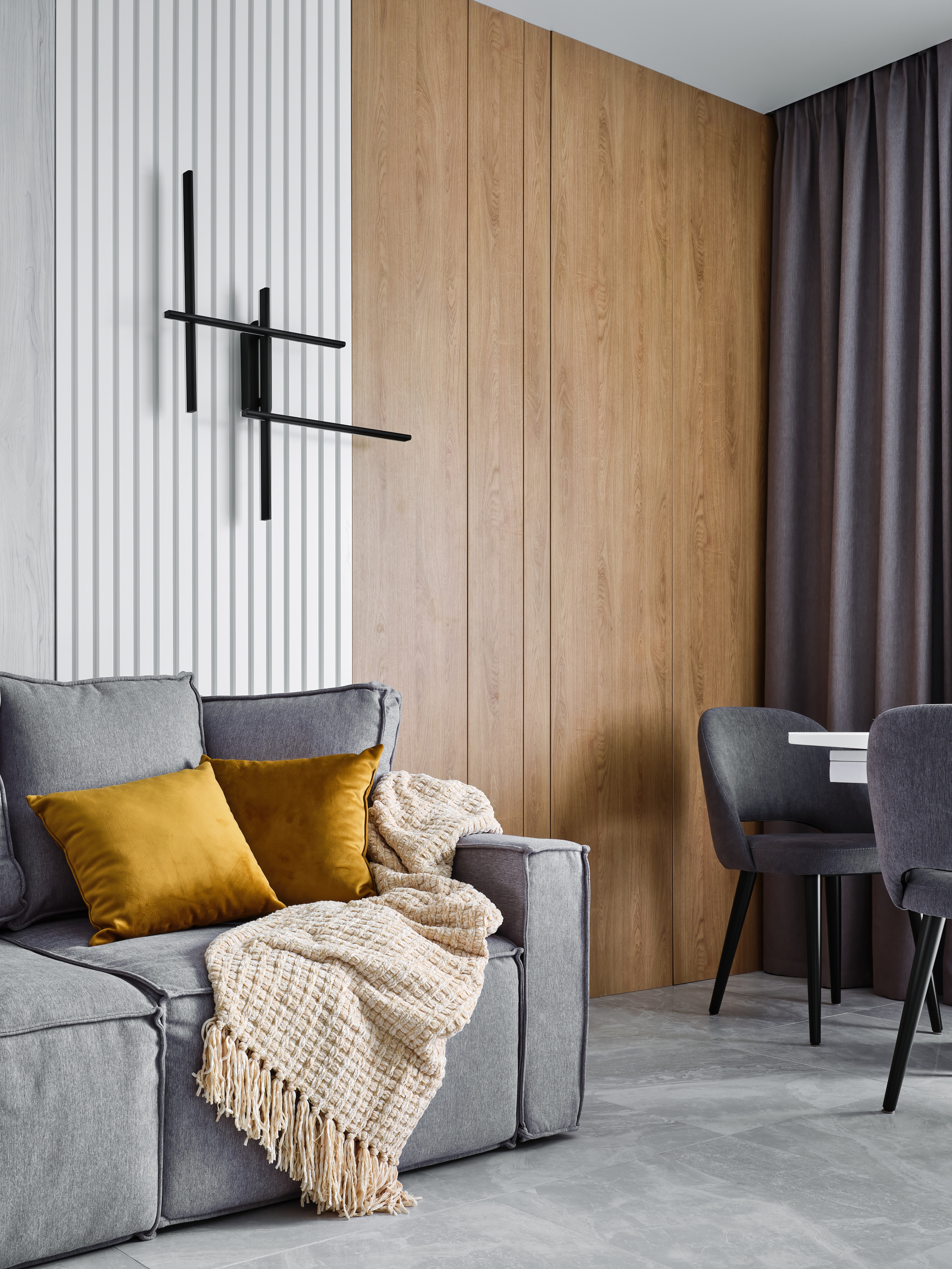 Стильная гостиная с серым диваном, желтыми акцентами в декоре и комбинированной отделкой стен. Дизайнер Анжелика Исаева, фотограф Сергей Денисенко, гармония уюта и современного минимализма в жилом интерьере.