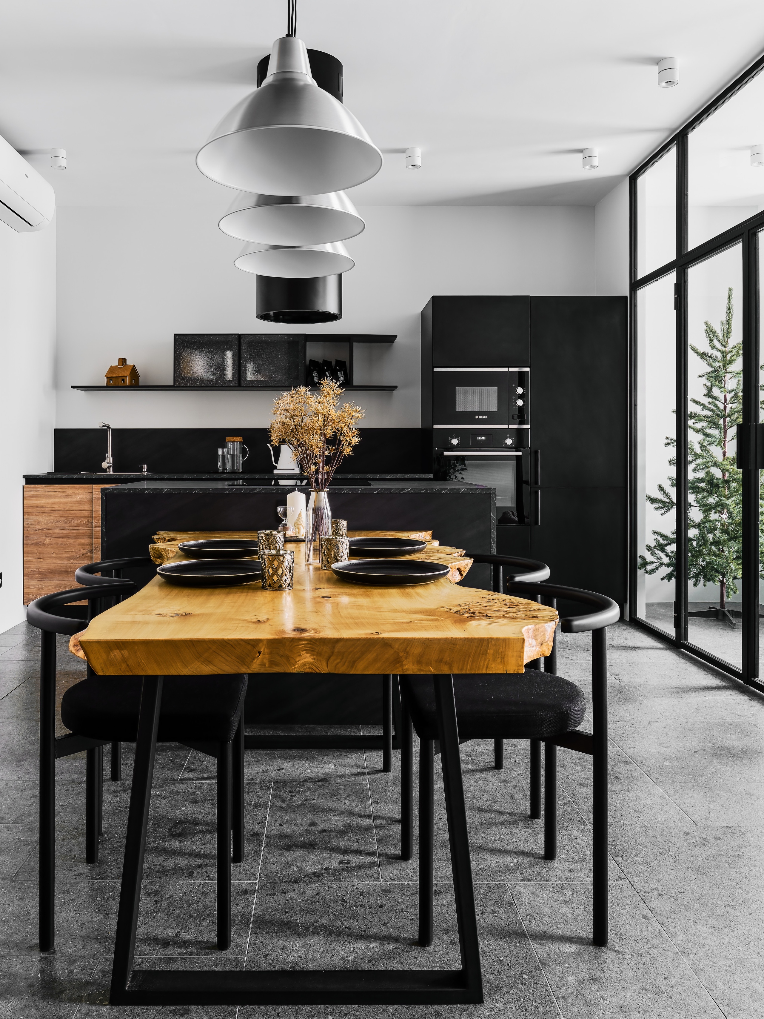 Кухня-столовая в современном стиле: натуральный деревянный стол, чёрные стулья, минималистичные подвесные светильники и строгая мебель. Интерьер создан Андреем Нелень и Екатериной Проскуряковой, фото Сергея Денисенко.