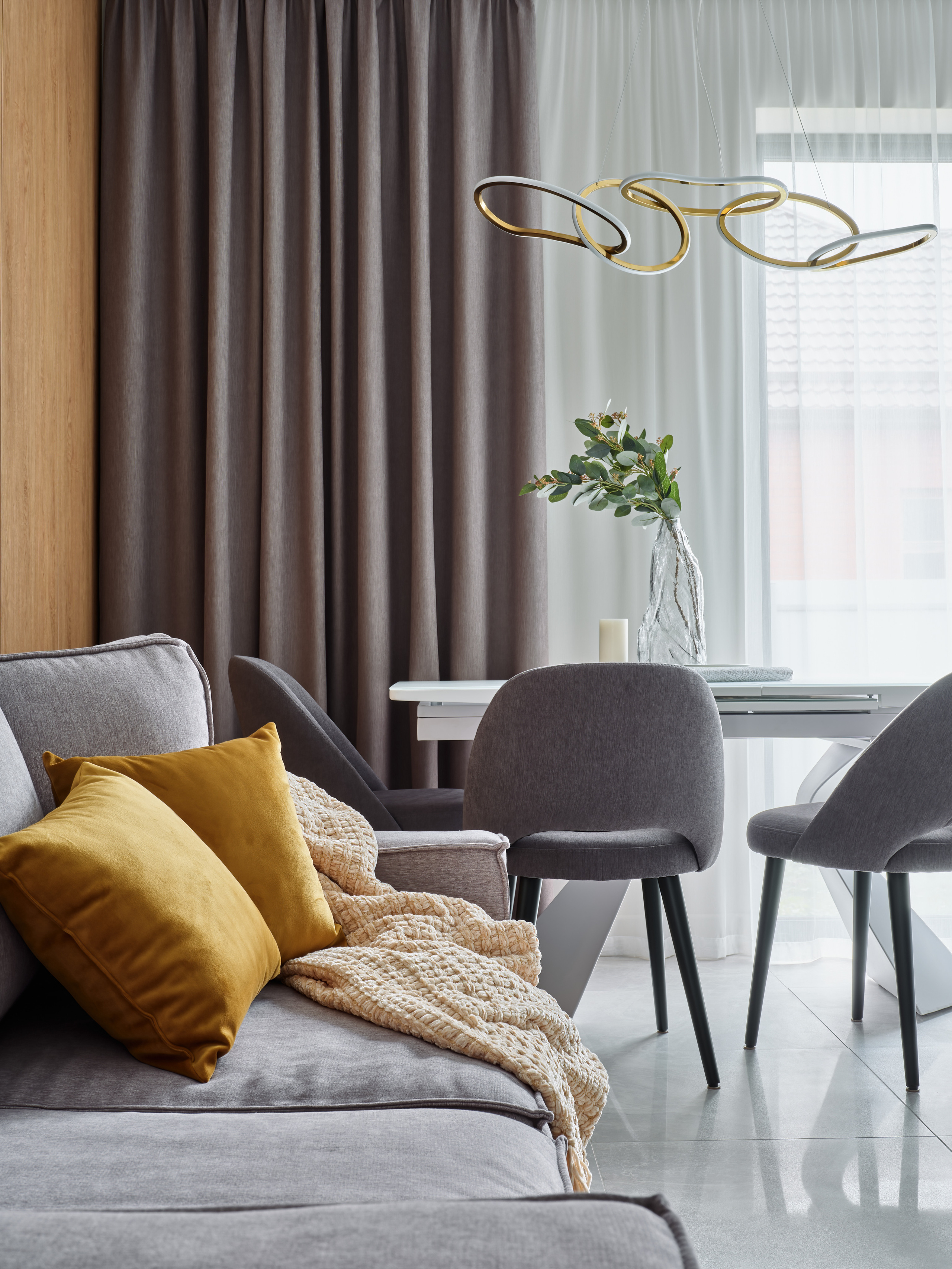 Совмещенная гостиная и столовая с серыми креслами, современным освещением и панорамными окнами. Дизайнерский проект Анжелики Исаевой, интерьерная фотосъемка Сергея Денисенко, стильный минимализм для городской квартиры.