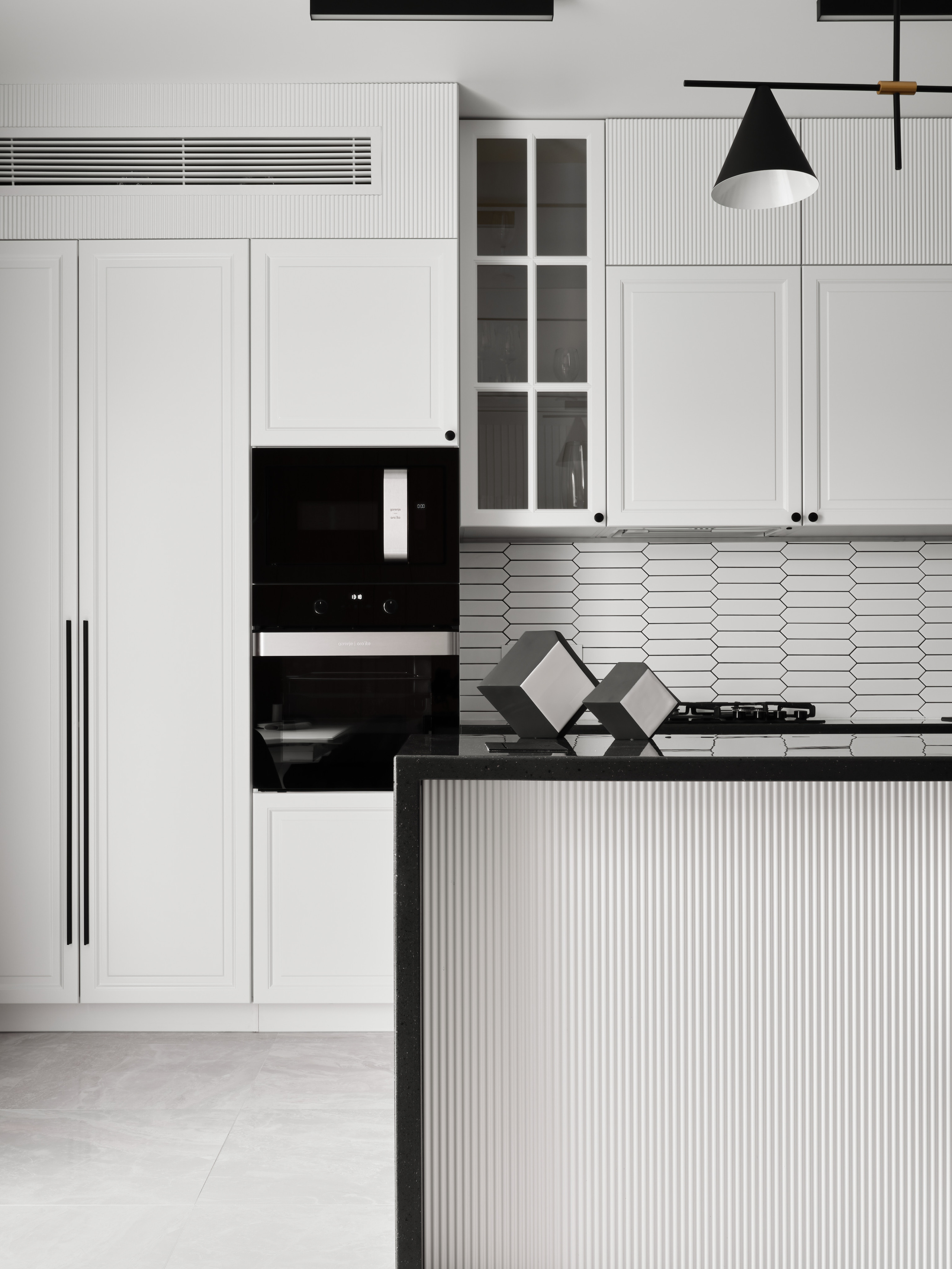 Белая кухня с акцентом на черный каменный остров и графичный фартук из плитки. Авторский проект дизайнера Анжелики Исаевой, профессиональная интерьерная съемка Сергея Денисенко, современный минимализм в городской квартире.