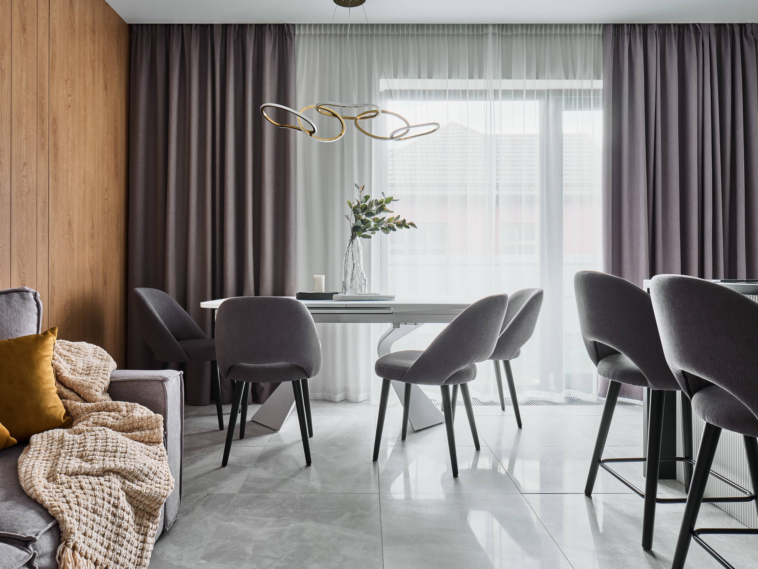 Современная столовая с обеденным столом, серыми стульями и панорамными окнами с текстильными шторами. Интерьер от дизайнера Анжелики Исаевой, фотосъемка Сергея Денисенко, гармоничный минимализм и светлое пространство.