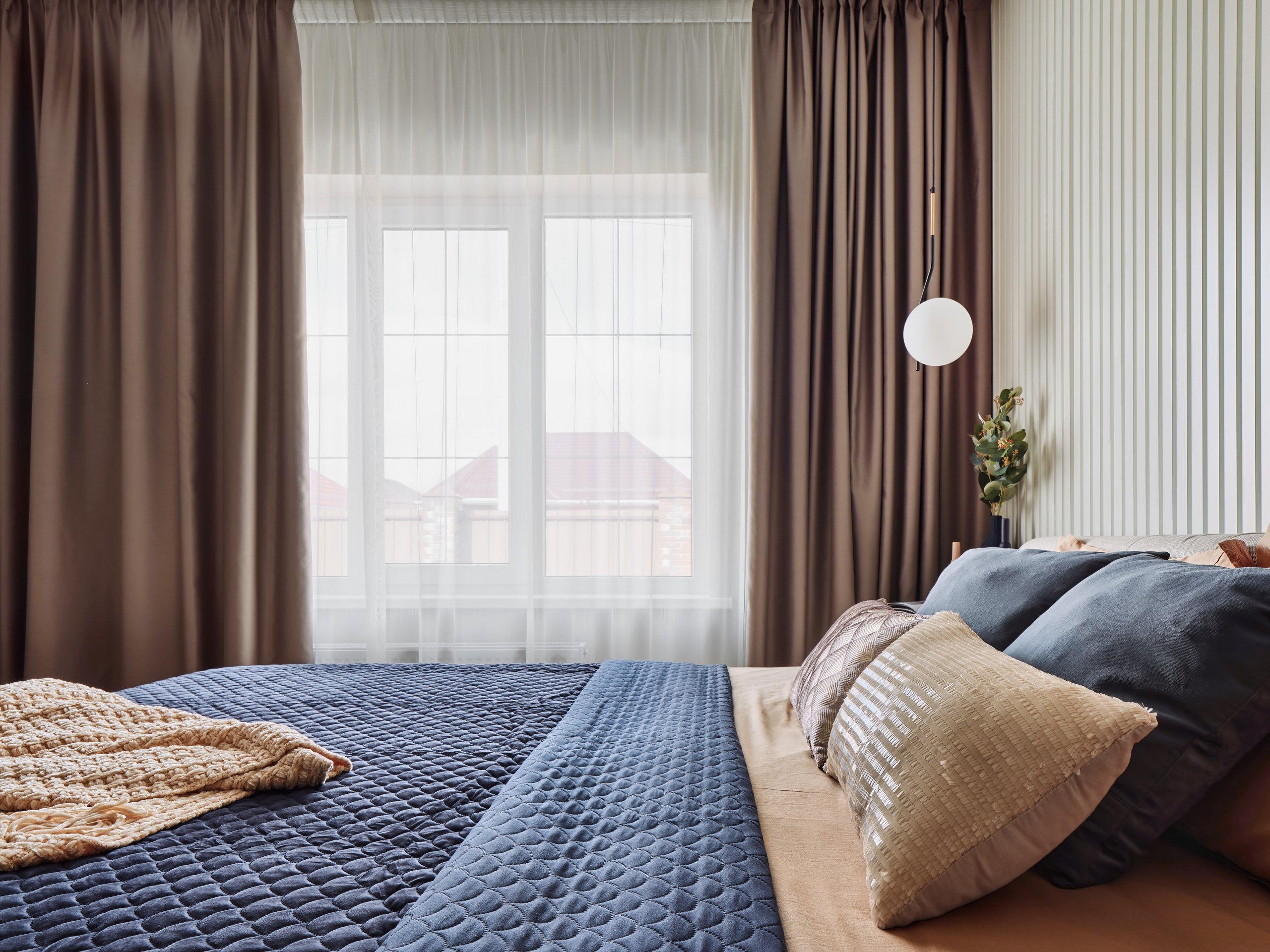 Современная спальня с панорамным окном, плотными шторами шоколадного оттенка, светлой отделкой стен и стильными подвесными светильниками. Дизайн Анжелика Исаева, интерьерная съемка Сергей Денисенко.