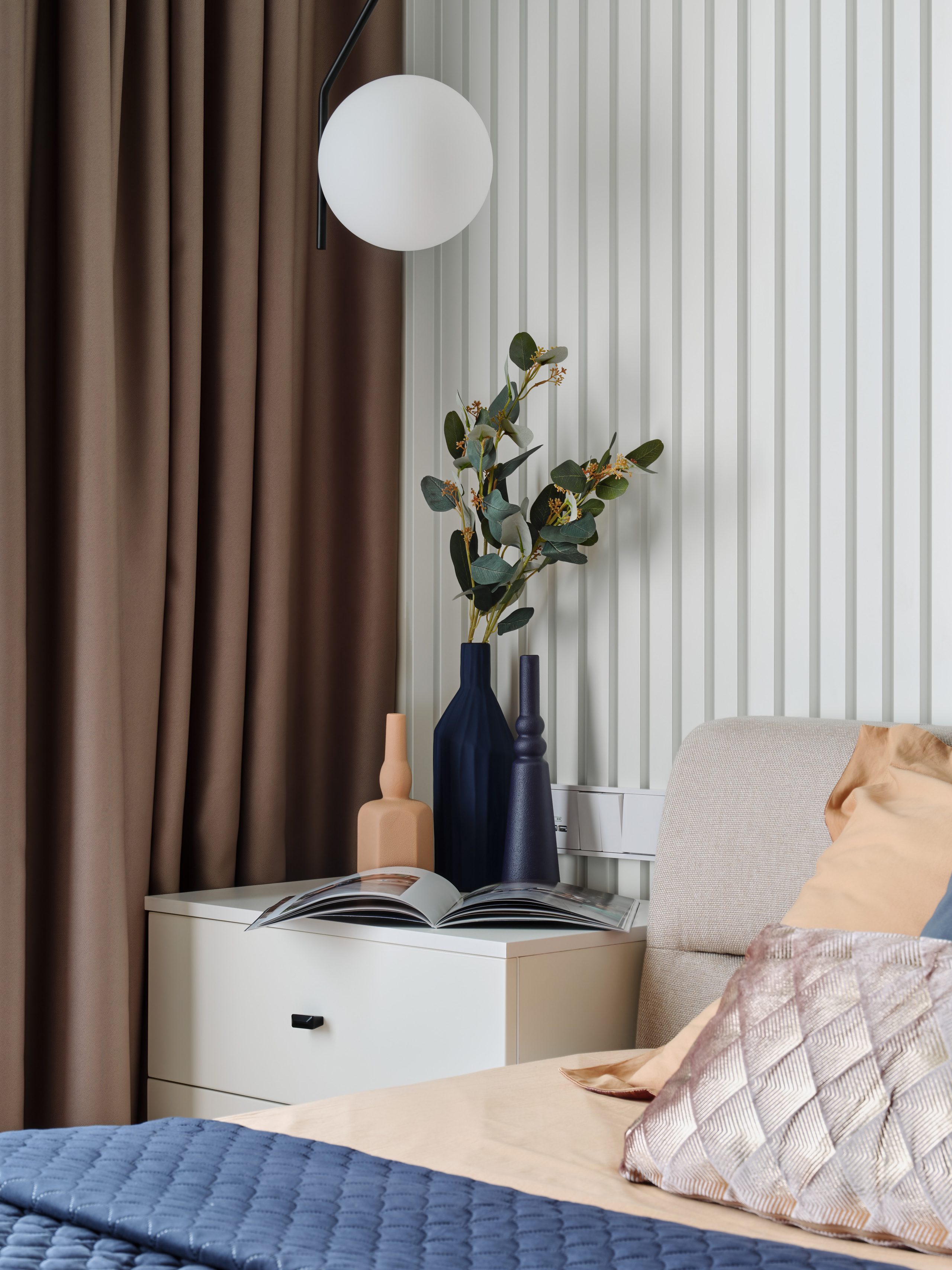 Прикроватная тумба с декоративными вазами и растением, мягким светильником и текстильными акцентами в спальне. Интерьер создан Анжеликой Исаевой, фотограф Сергей Денисенко.