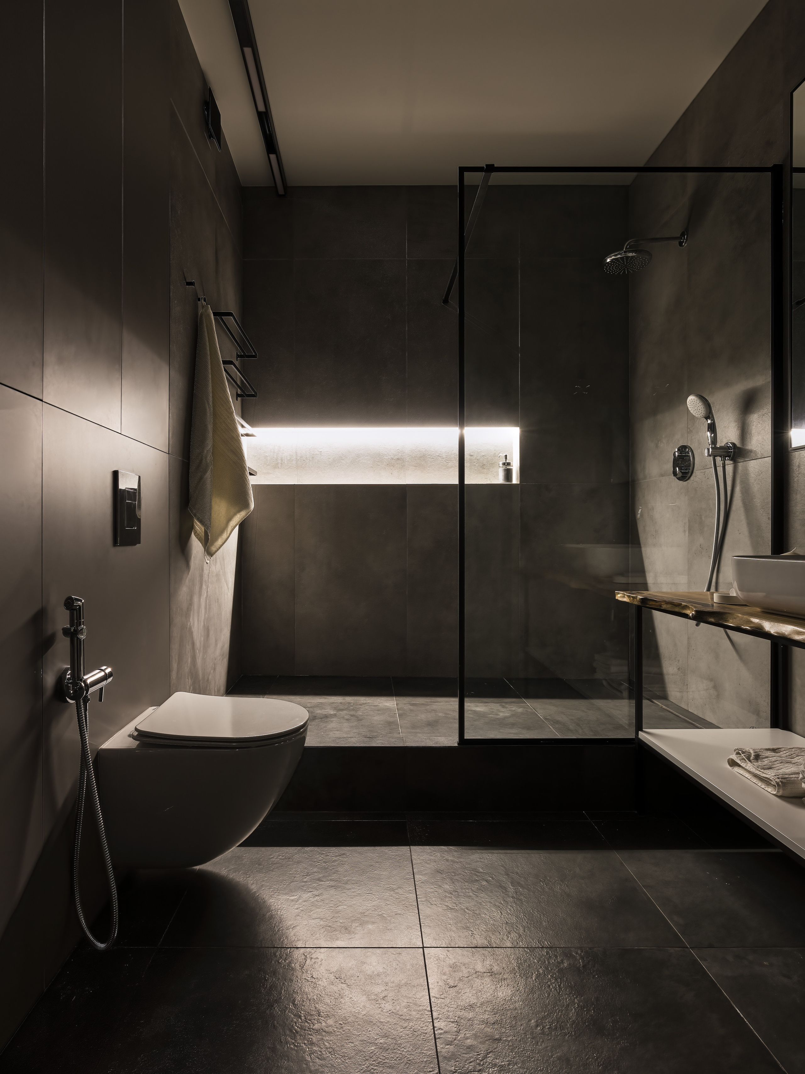 Стильная ванная комната с душевой кабиной в тёмной плитке, подвесным унитазом и встроенной подсветкой. Современный минимализм от дизайнеров Андрея Нелень и Екатерины Проскуряковой, фотограф интерьера Сергей Денисенко.