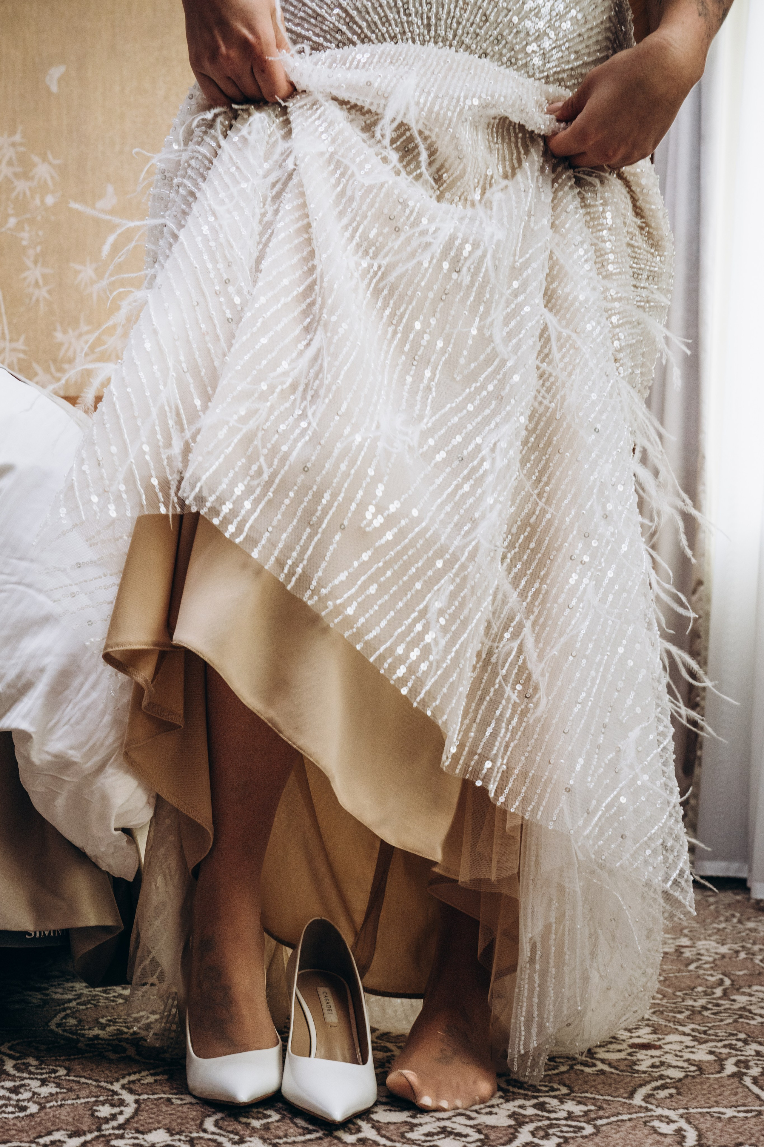 Невеста сидит в кресле, пока визажист наносит ей макияж — профессиональная свадебная фотосъемка в Москве с акцентом на подготовку.