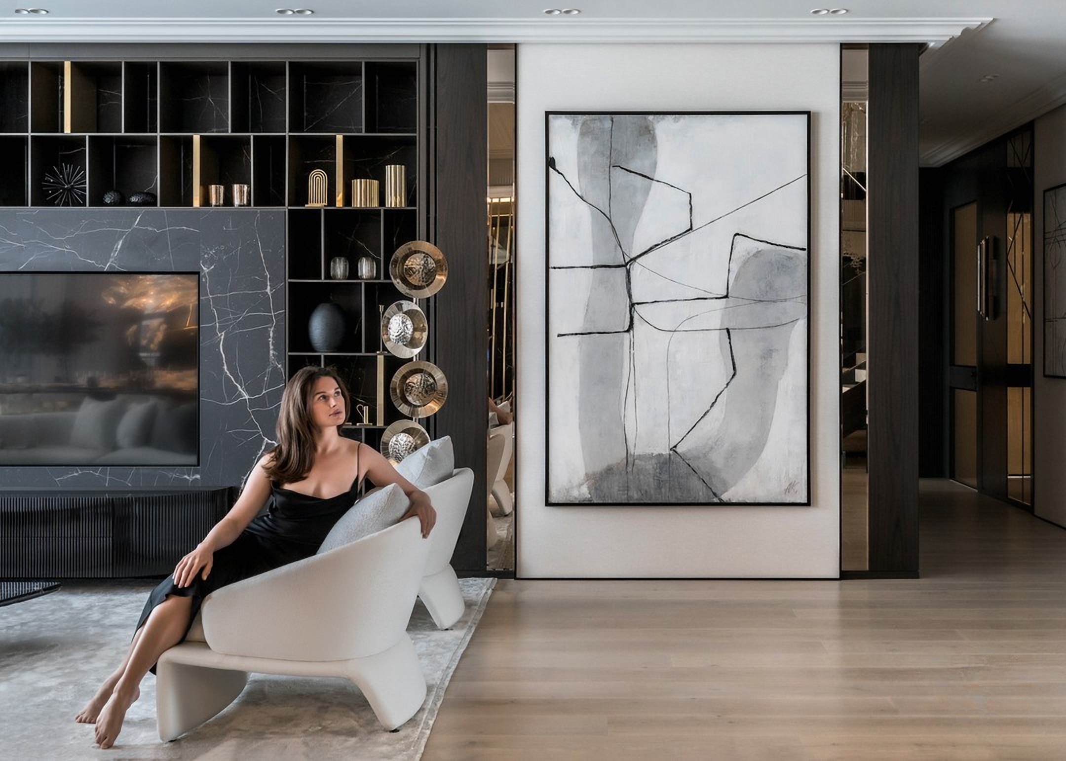 Девушка в интерьере гостиной с абстрактной картиной и креслами цвета айвори — современный дизайн
