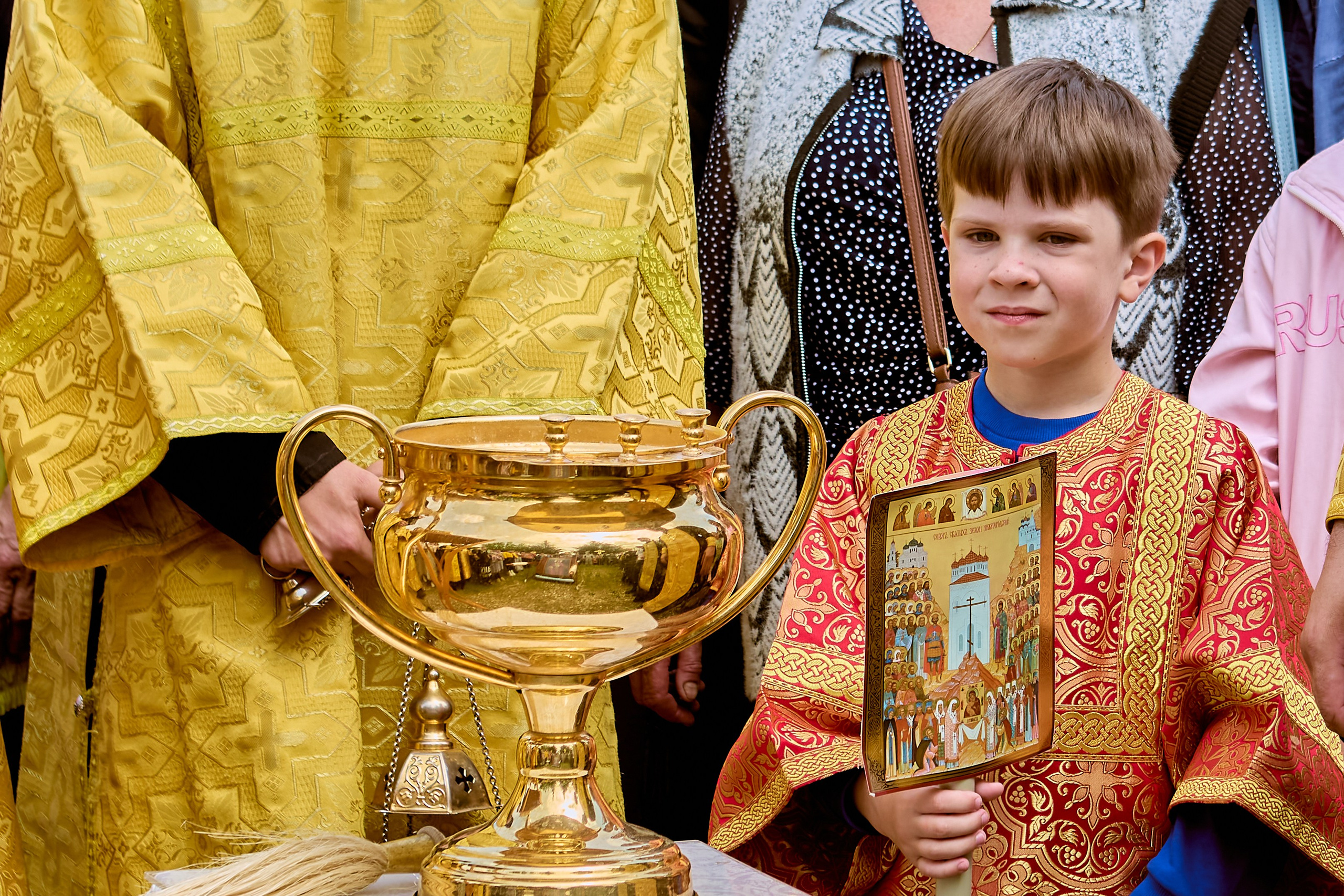 Малыш - алтарник в стихаре у чаши для крапления с водой