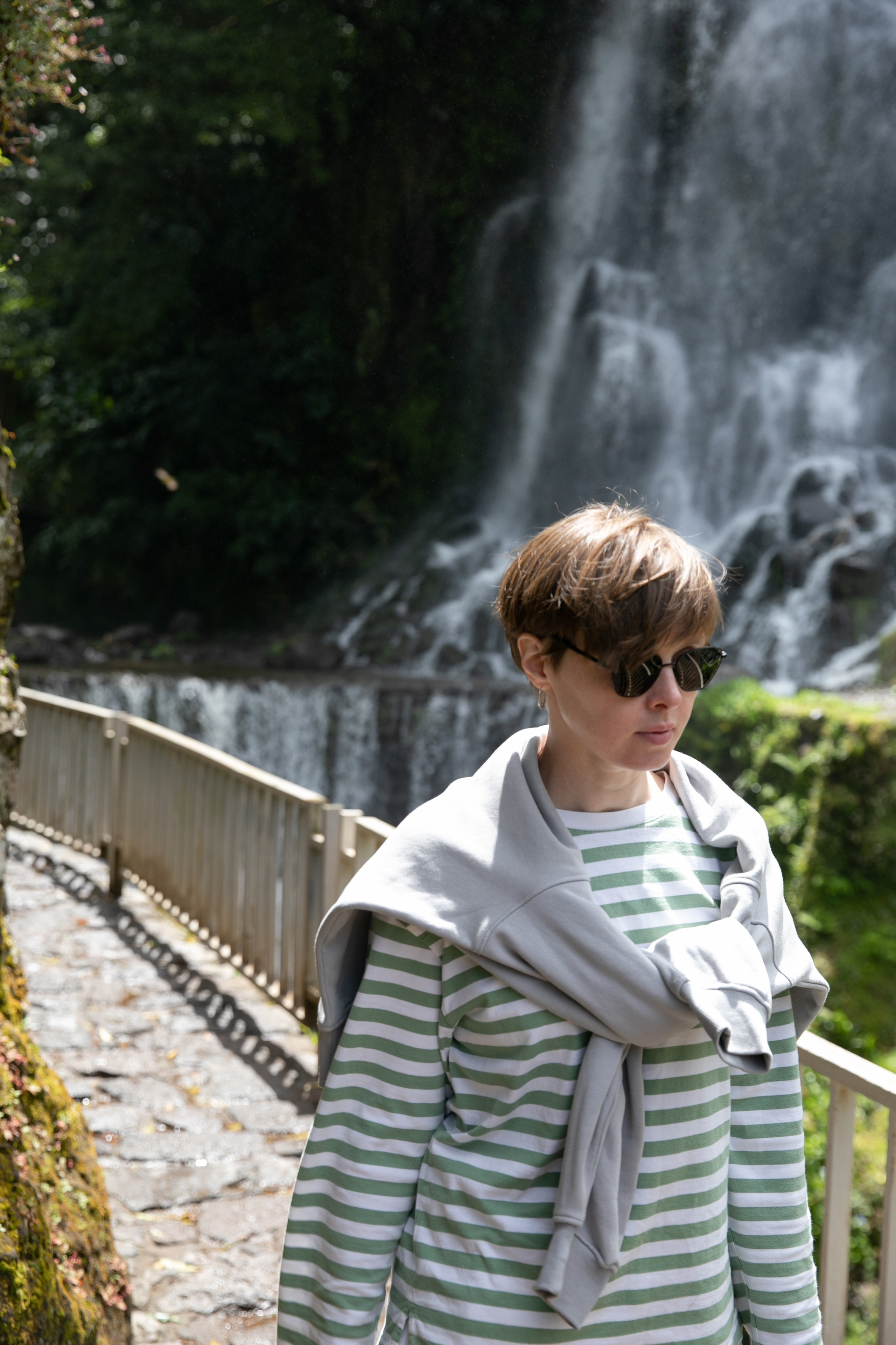 Women wander through the stunning landscapes of the Azores, surrounded by green hills, the ocean, and an open sky above