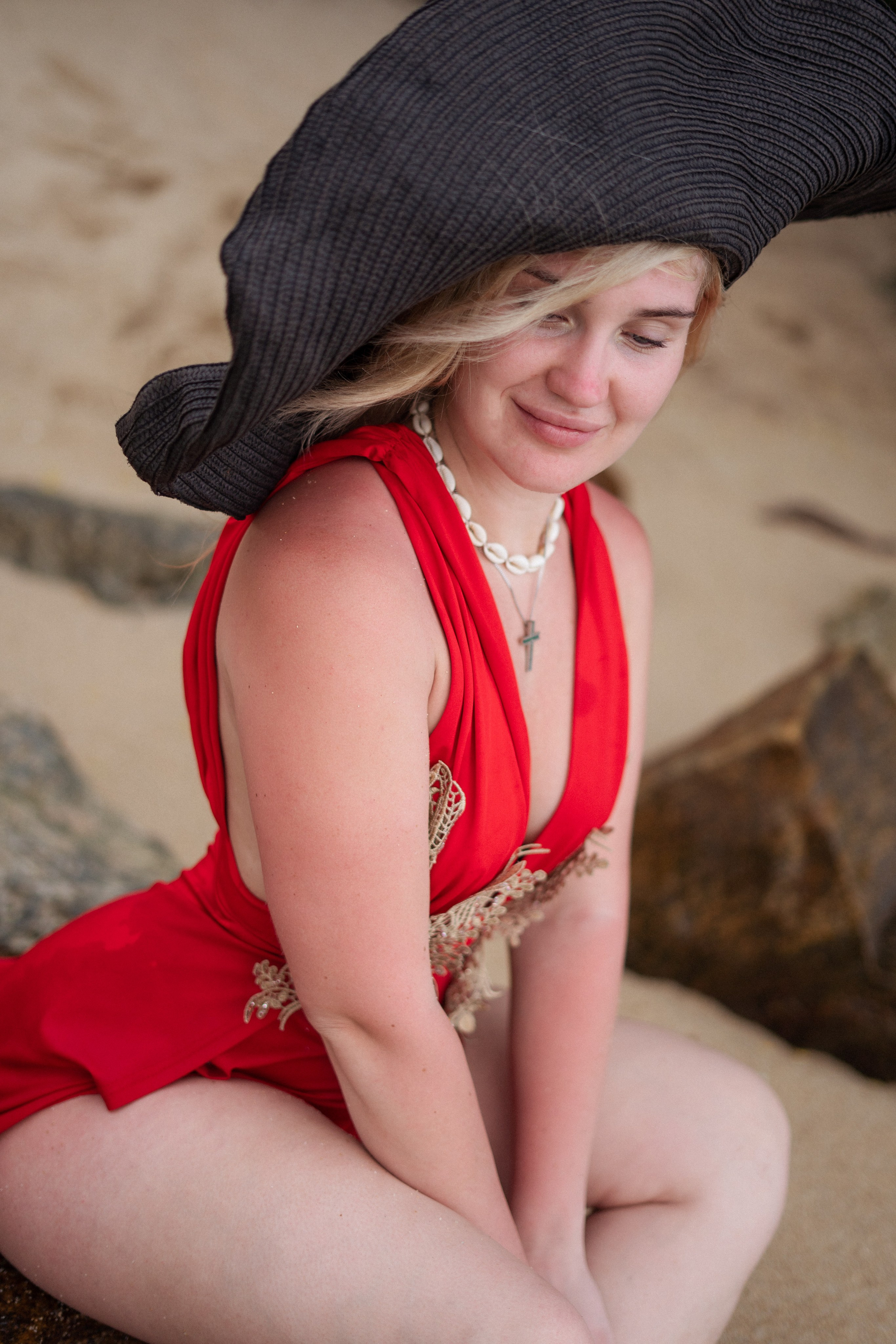 a beautiful blonde in a red dress taking steps along the ocean shore