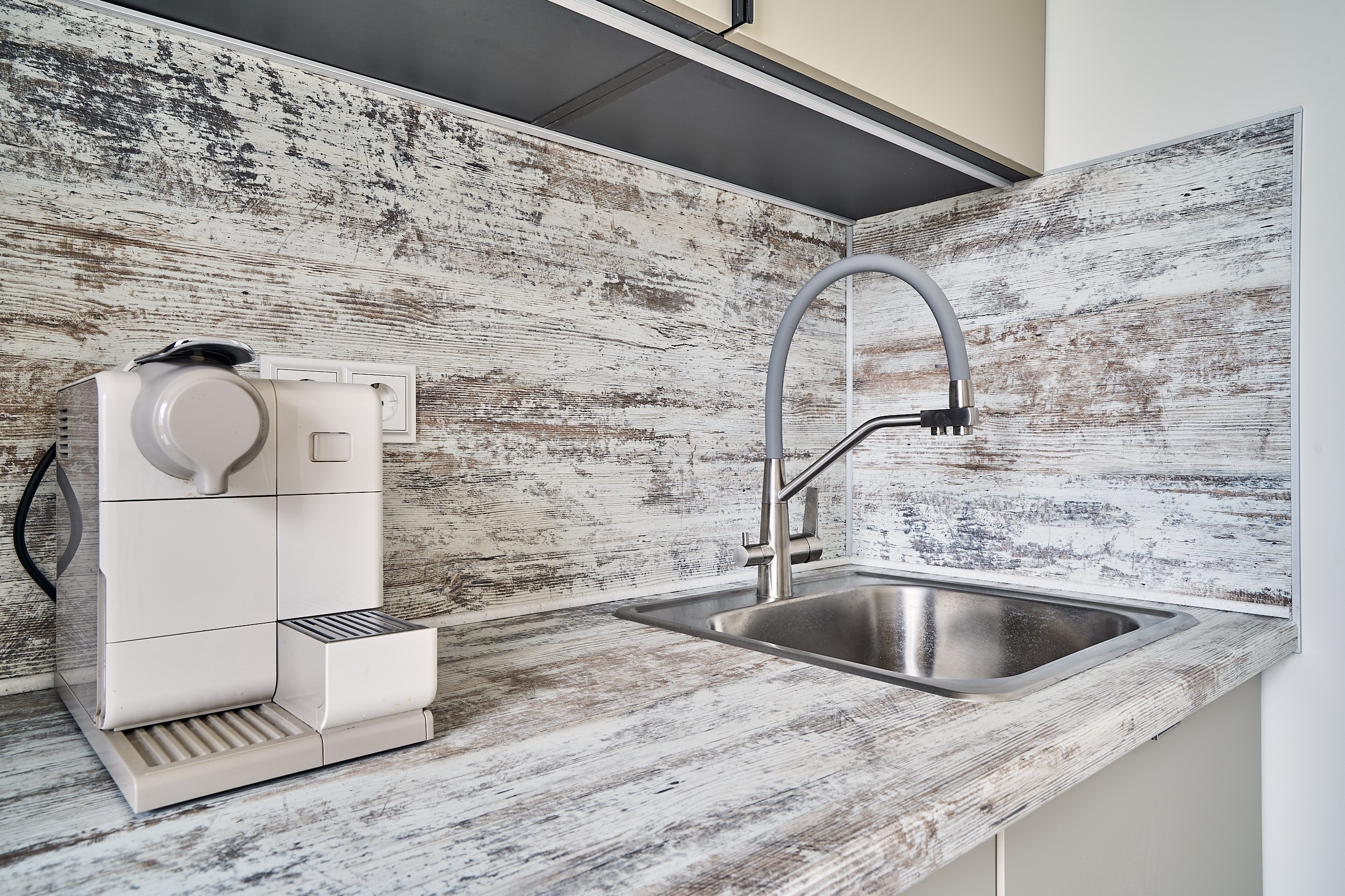 Интерьерная съемка на кухне двухкомнатной квартиры с крупным планом кофемашинки и функционального смесителя