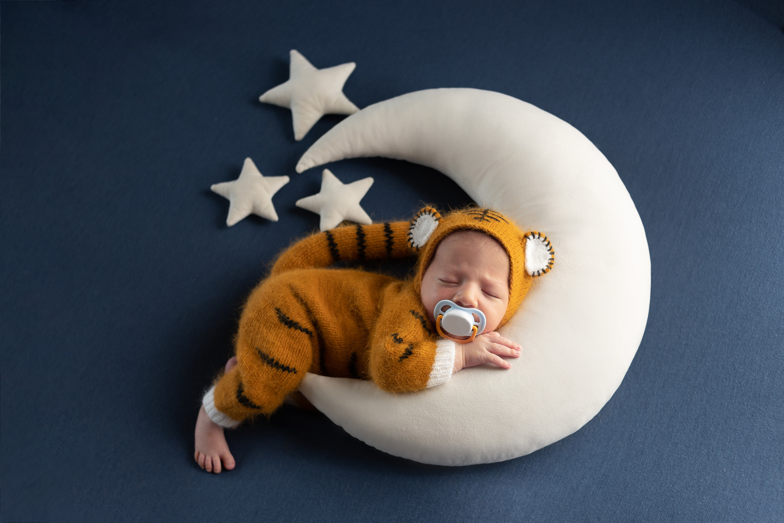 Новорождённый в костюме тигра на синем фоне и белом месяце