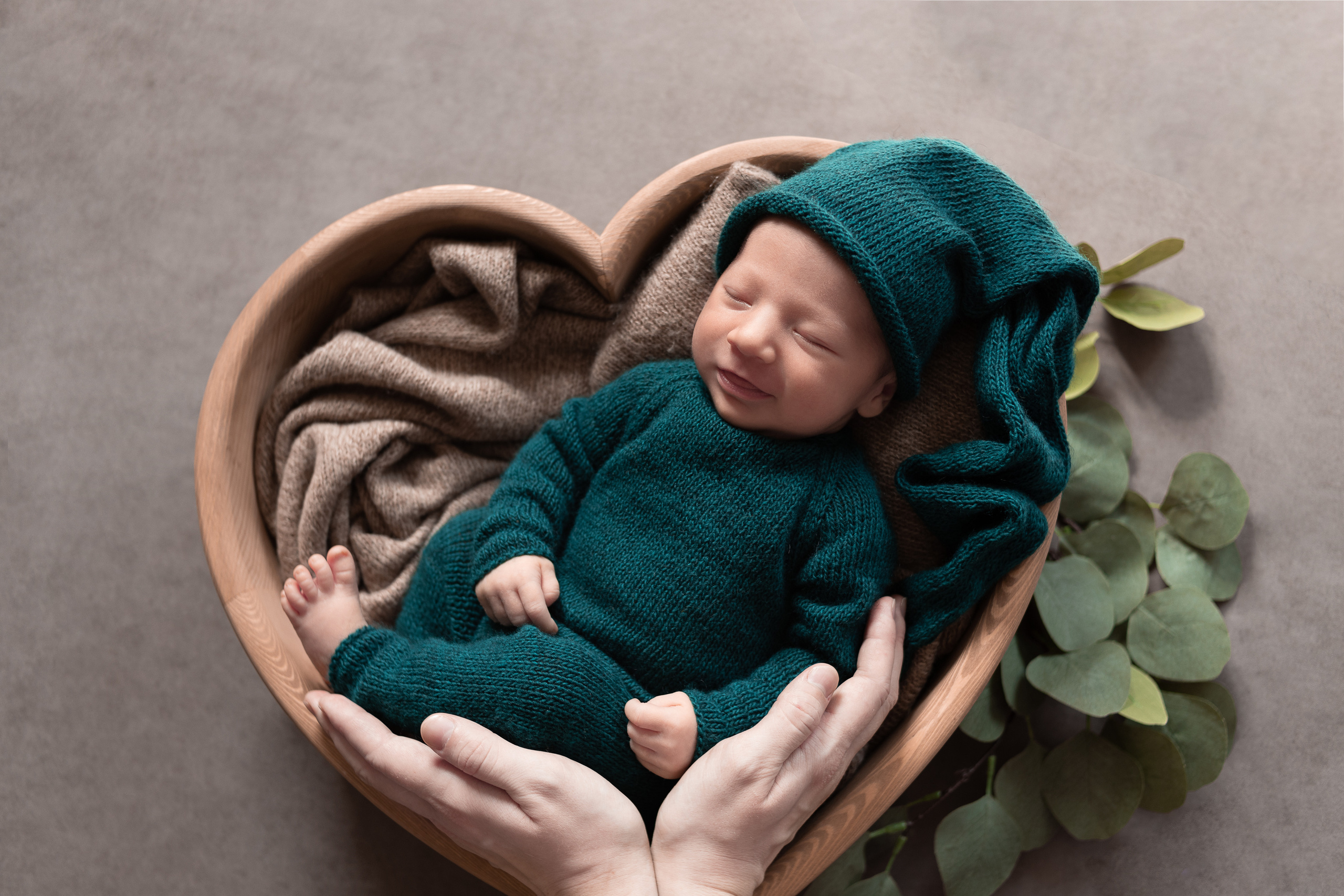 Руки мамы обнимают сыночка в зеленом костюме гномика