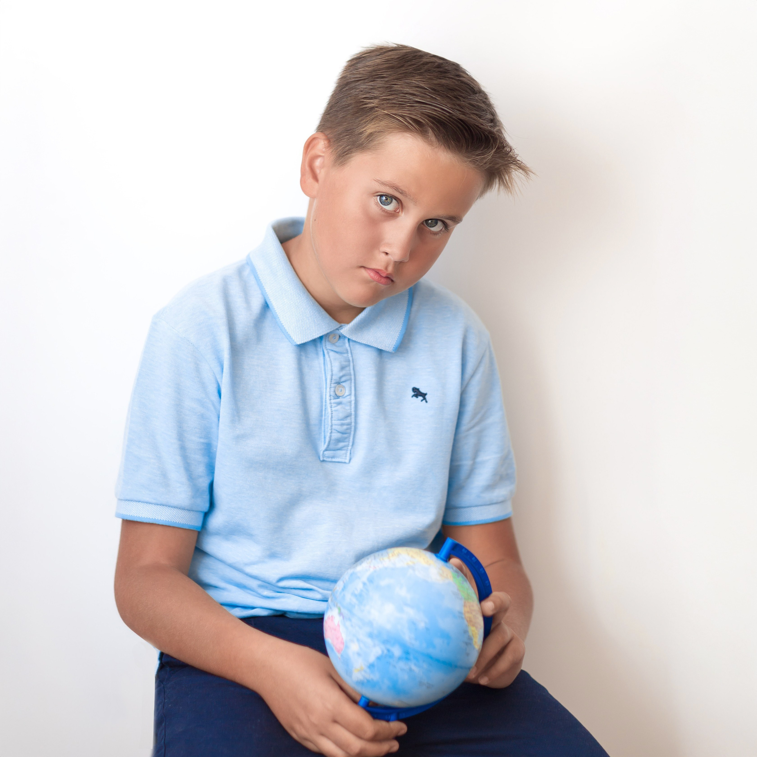 Мальчик держит глобус, сидит за партой, школьная фотосессия