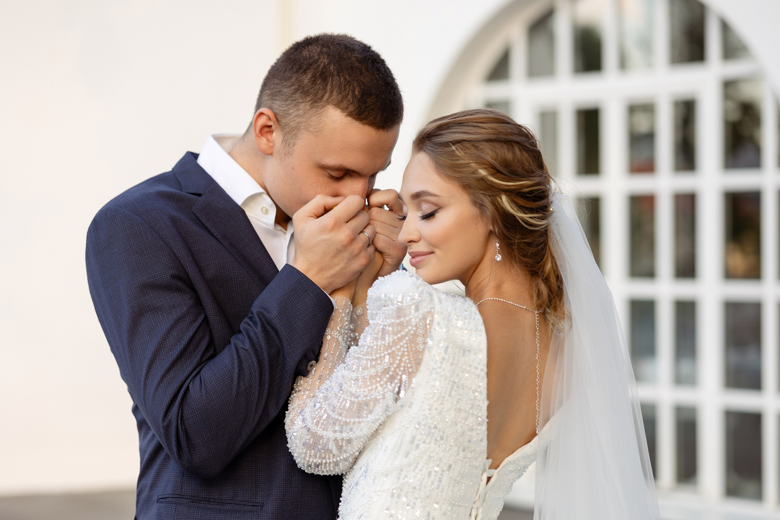 У арочного окна молодые. Жених целует руки возлюбленной.