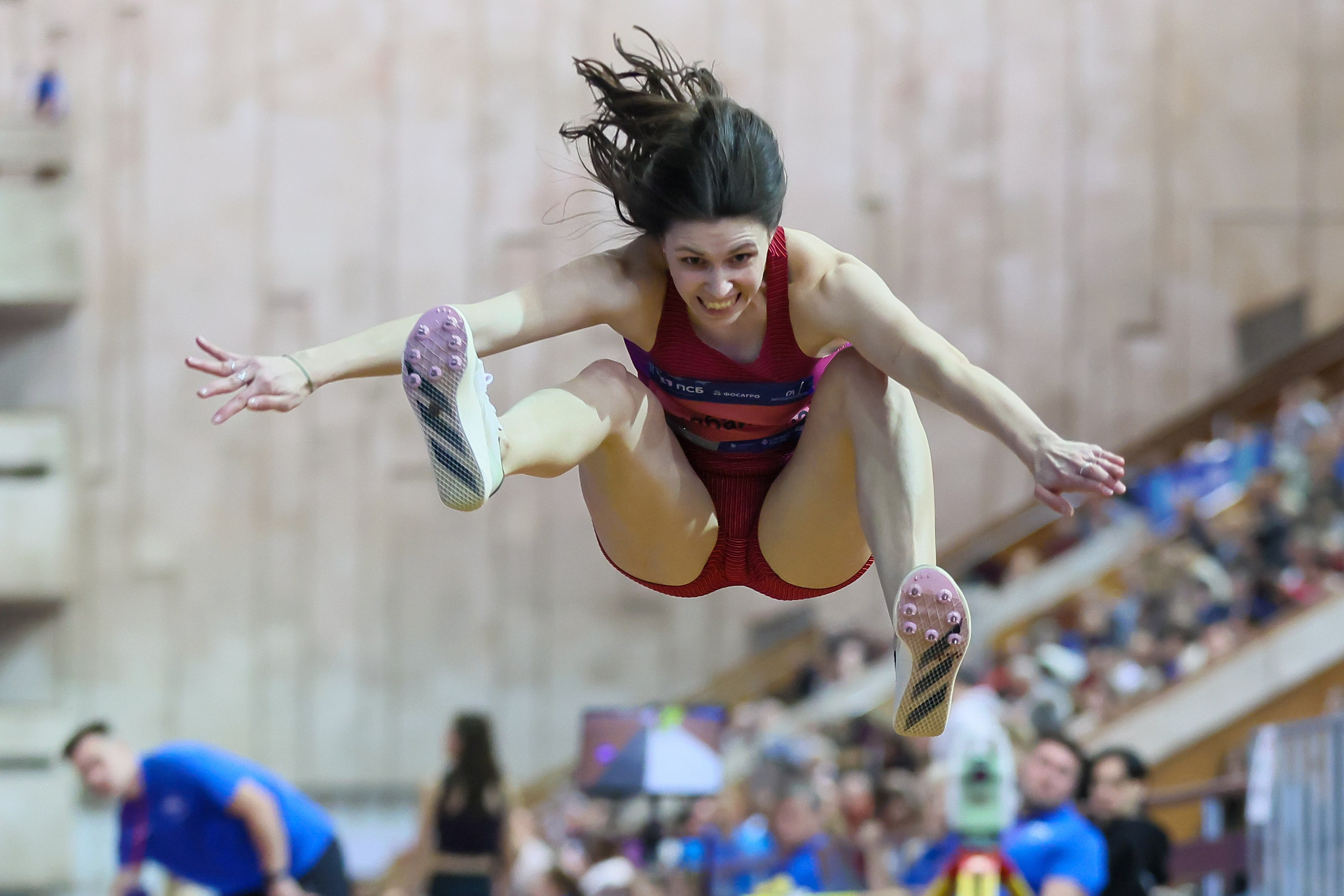 Прыгунья в длину красиво летит над ямой с песком