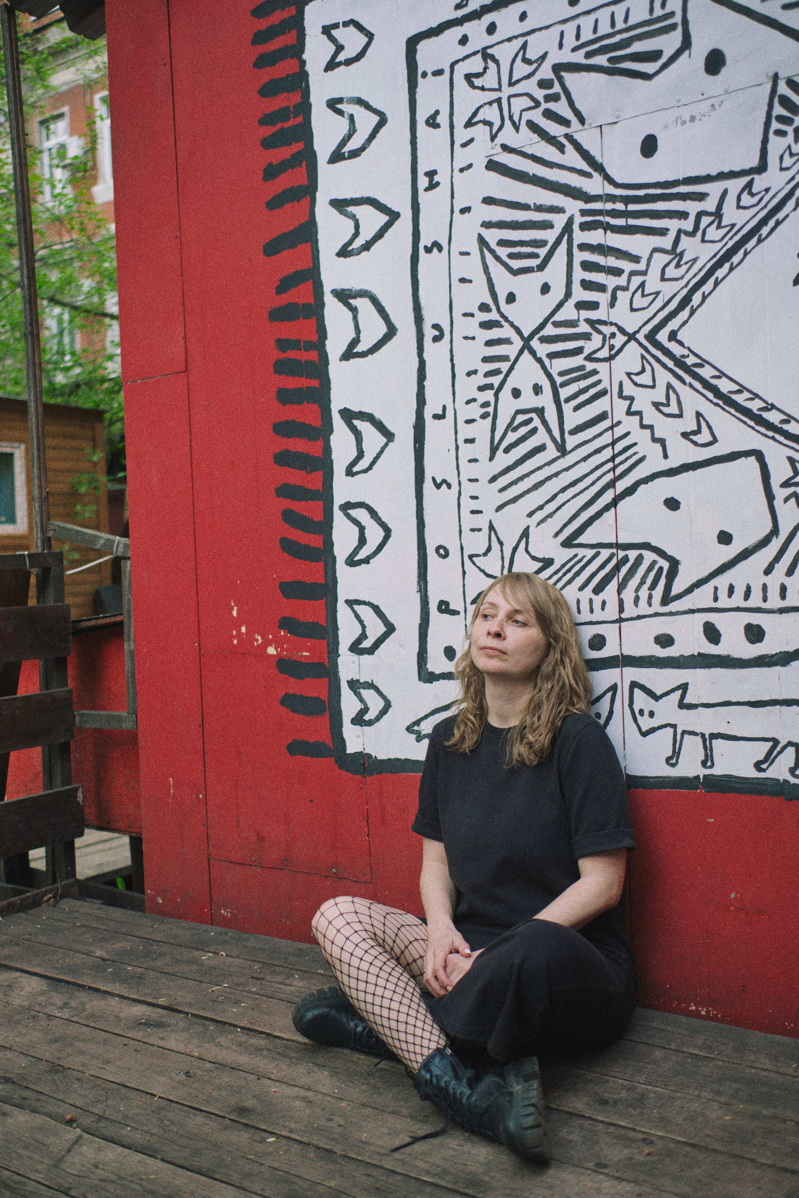 женщина сидит у стены со скрещенными ногами