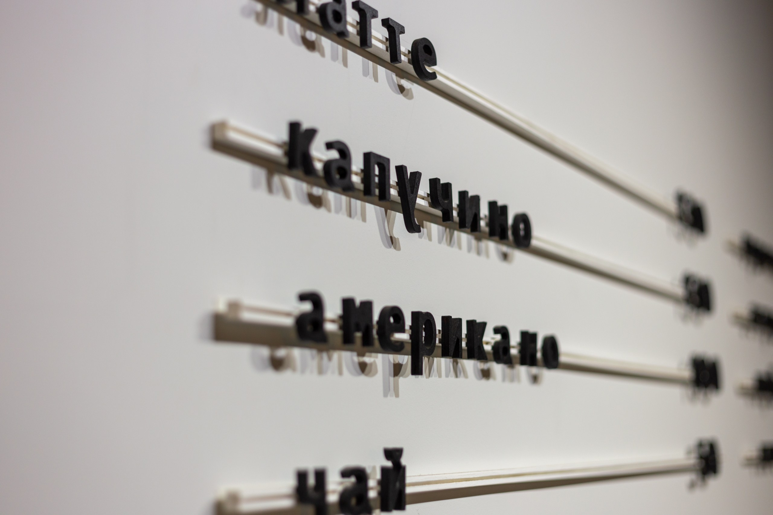 Крупно надписи на стене с видами кофе. Меню кофейни на белой стене объемными черными буквами.